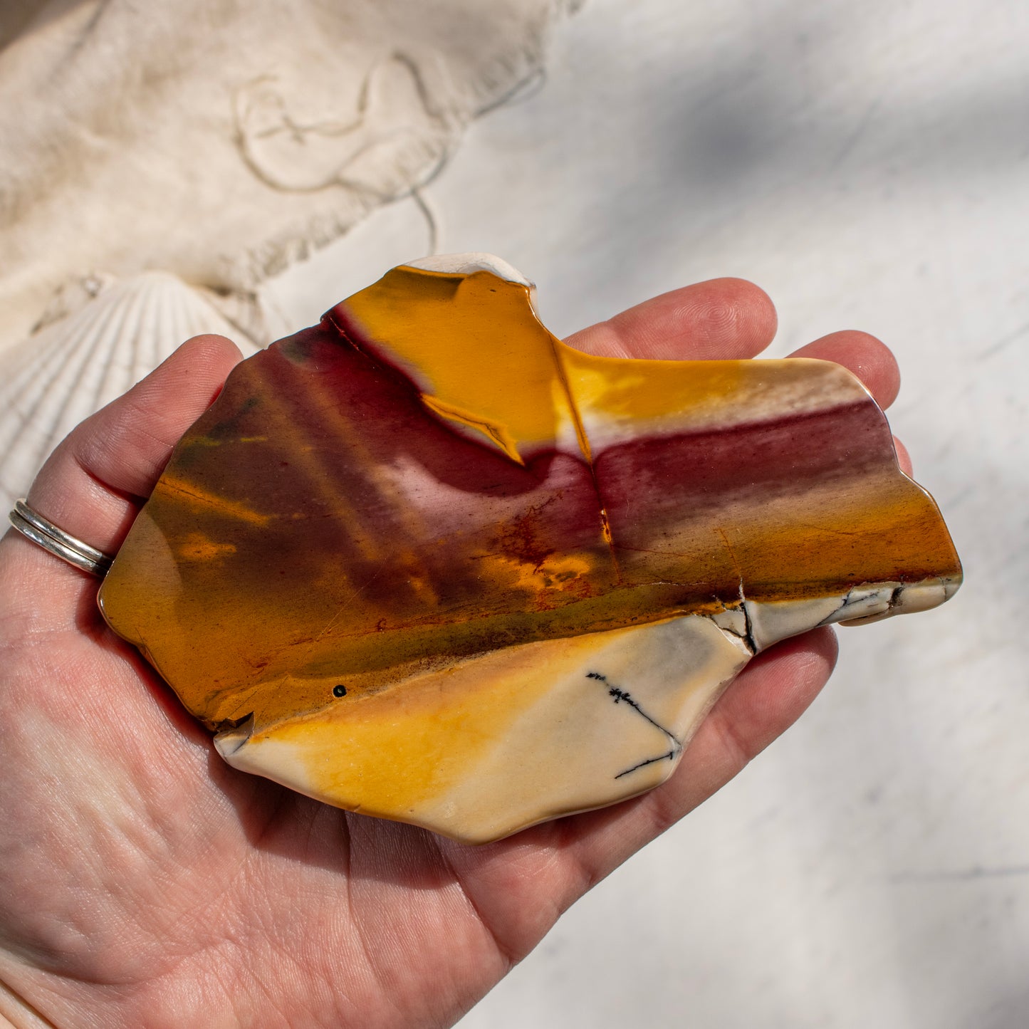 Hand holding a piece of multicolored stone with a blurred natural background