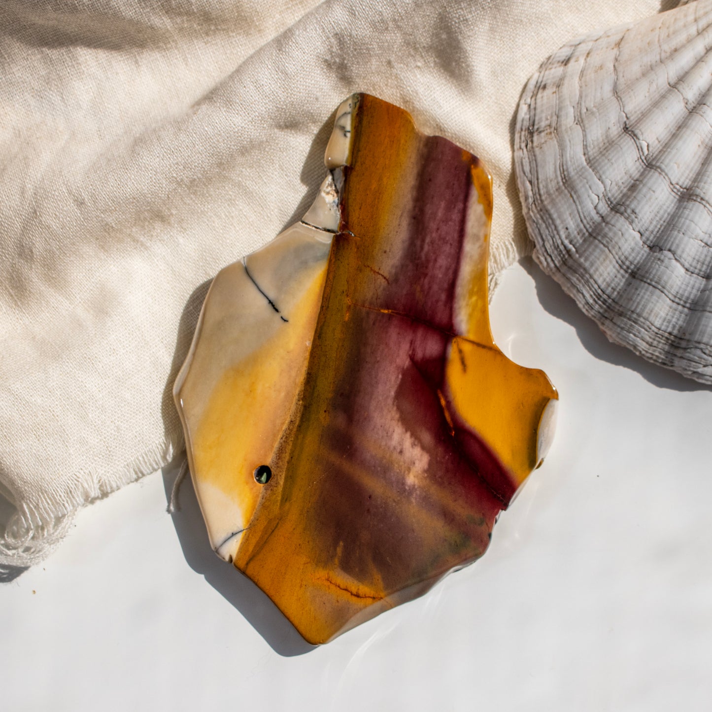 Polished stone with a shell on a textured fabric background