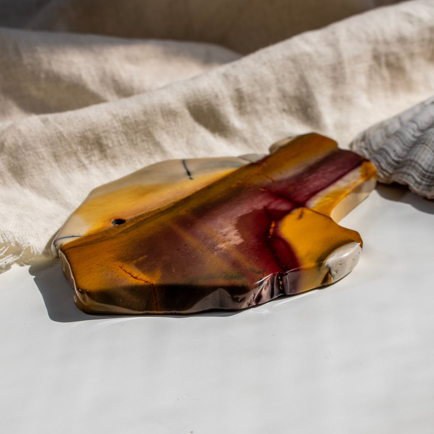 Polished stone with brown and red hues on a light fabric background