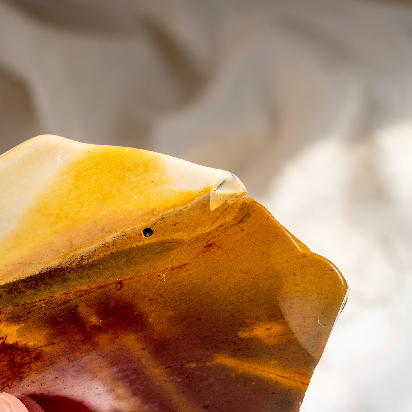 Close-up of a polished mookaite crystal, against a blurred background