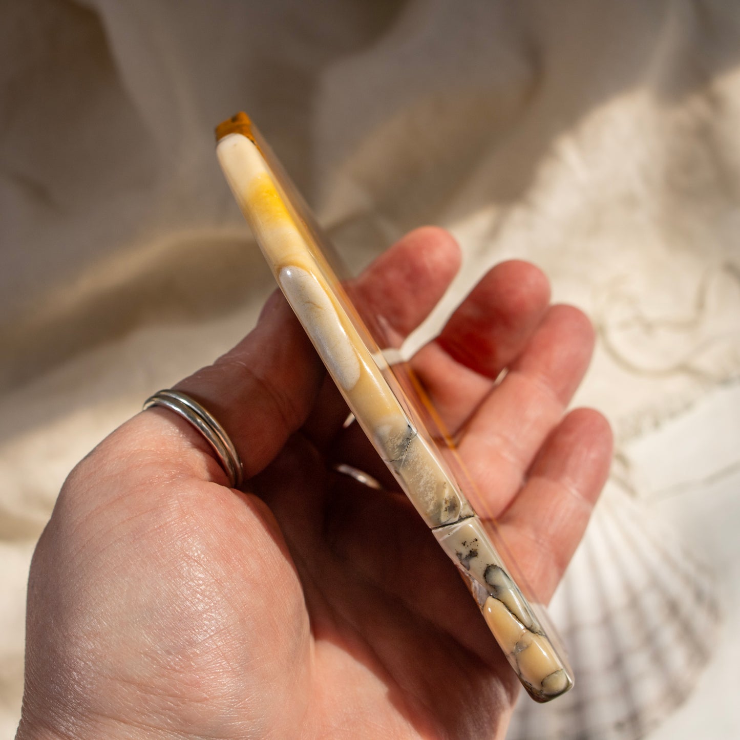 Hand holding a mookaite slab with a neutral background