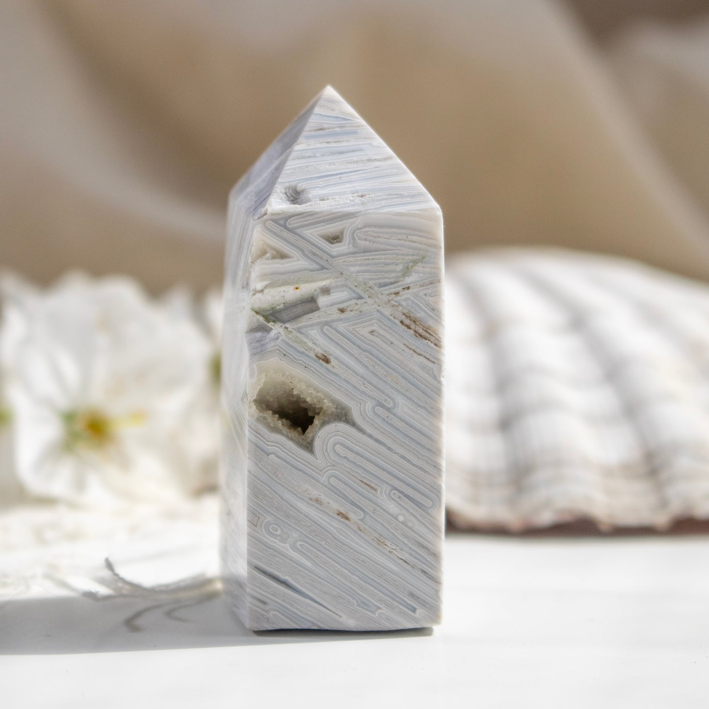 Marble-patterned tower-like object on a neutral background with flowers