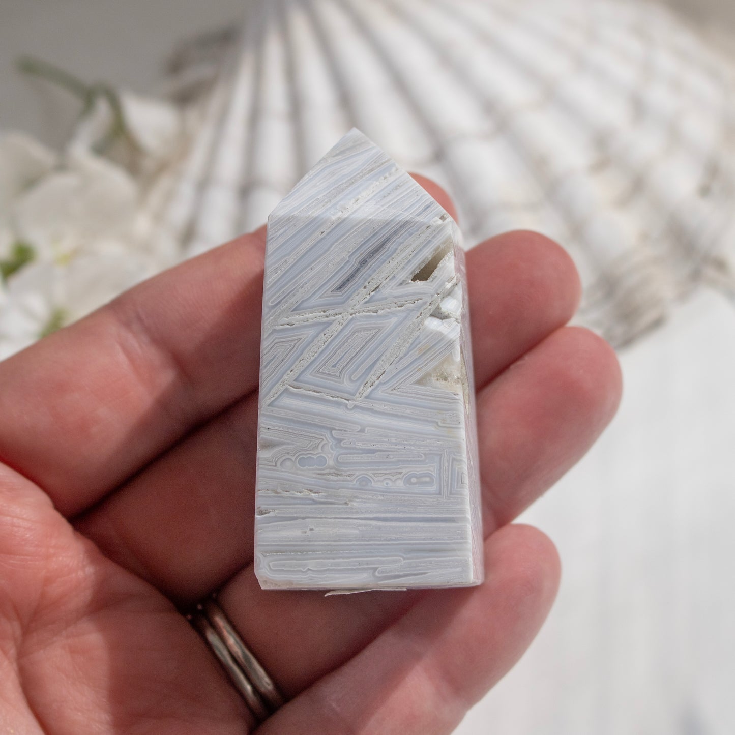 Hand holding a rectangular stone with marbled pattern against a blurred natural background