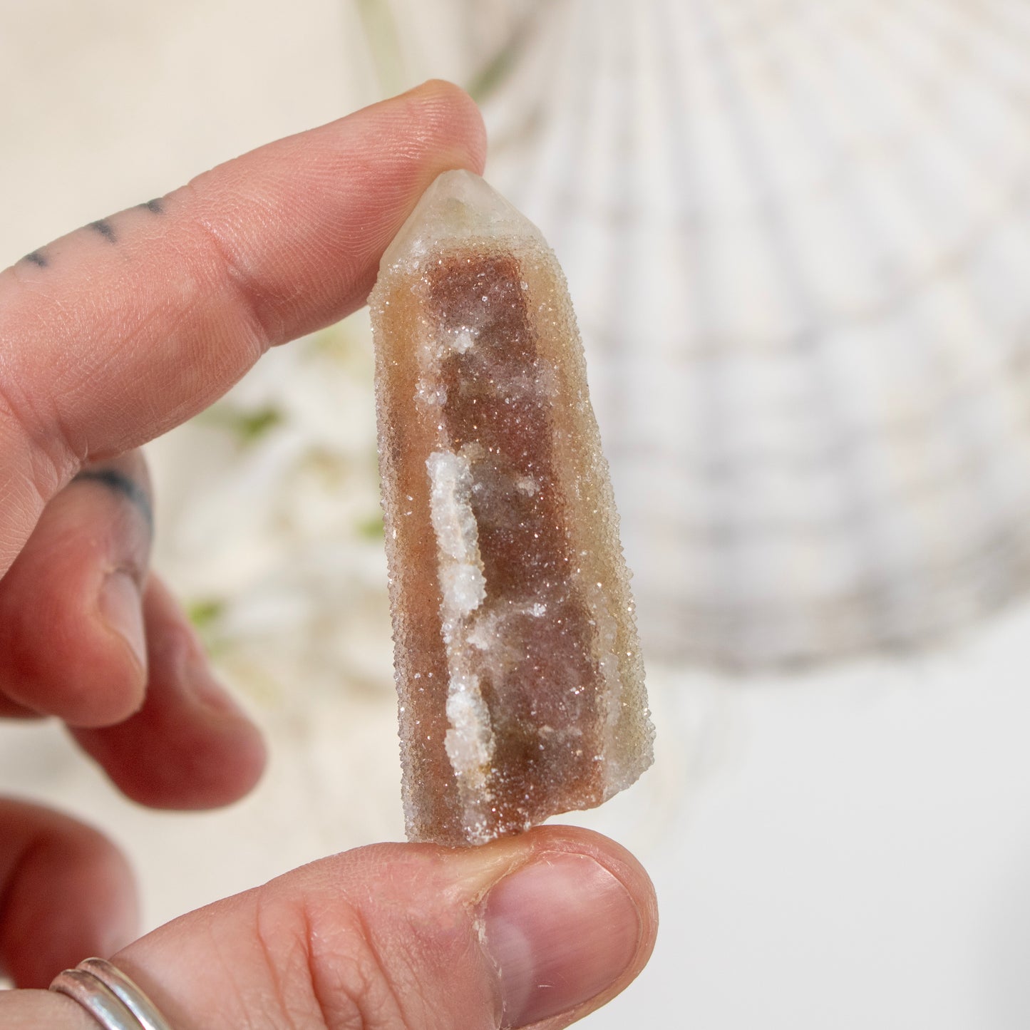 Hand holding a crystal with a blurred natural background