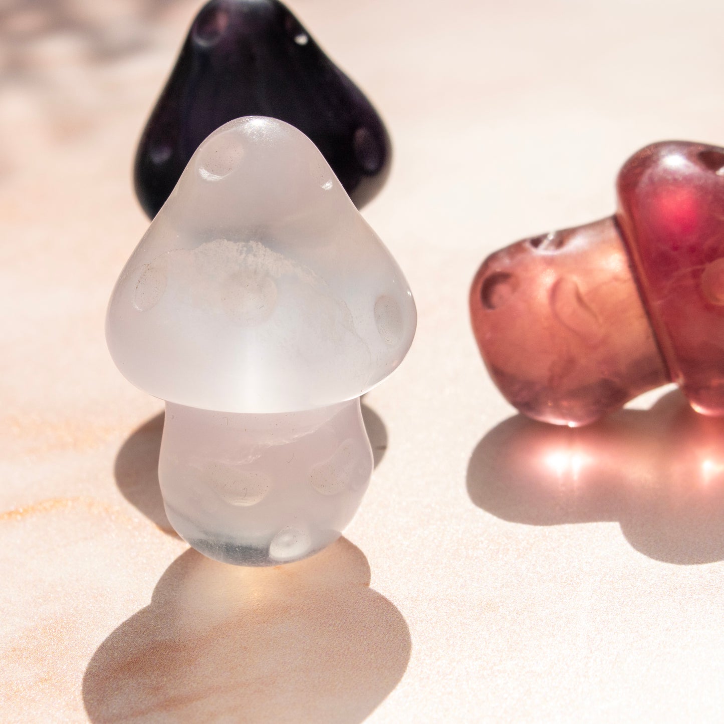 Three fluorite mushrooms in black, white, and red on a reflective surface.