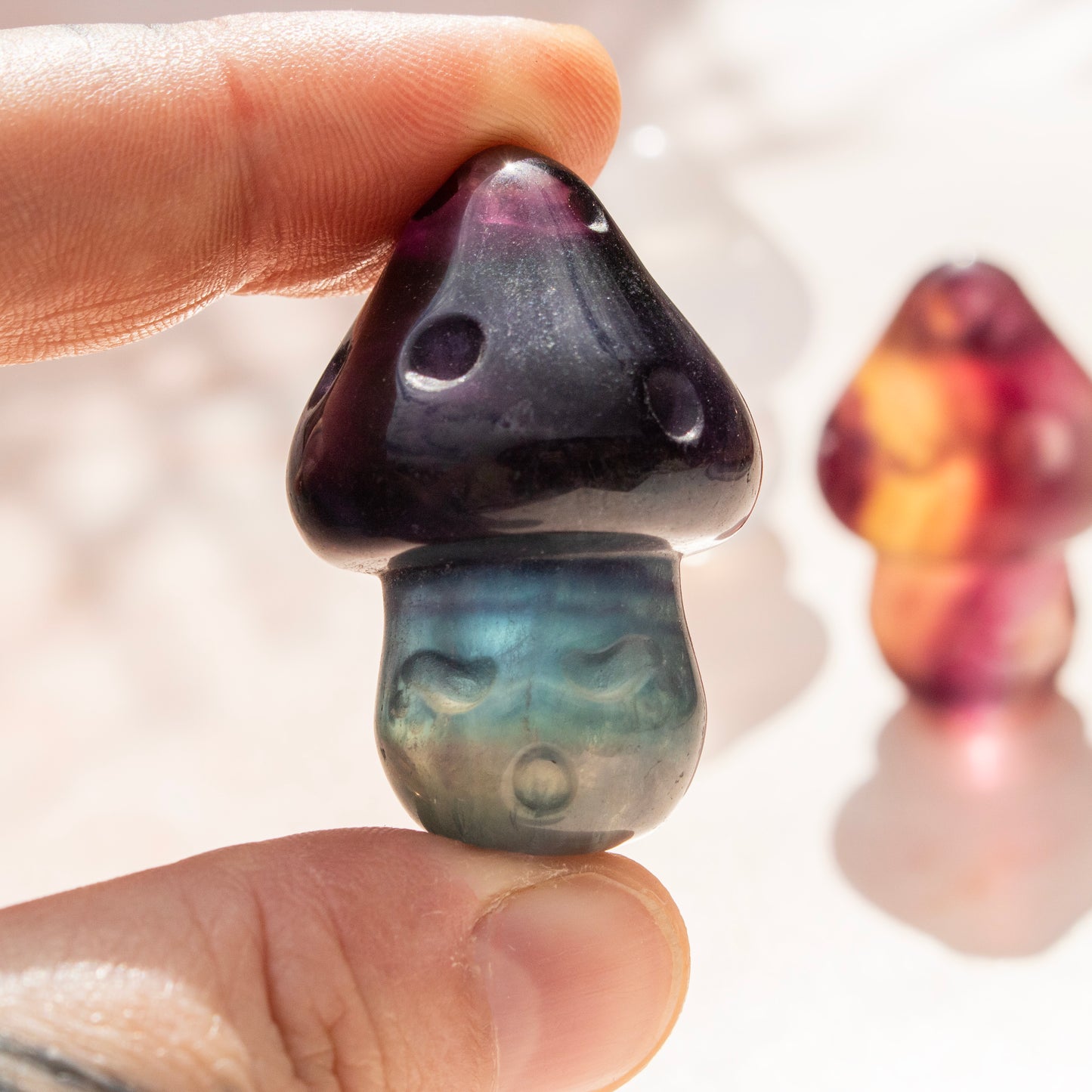 Hand holding a dark-colored stone with a smooth surface, blurred background