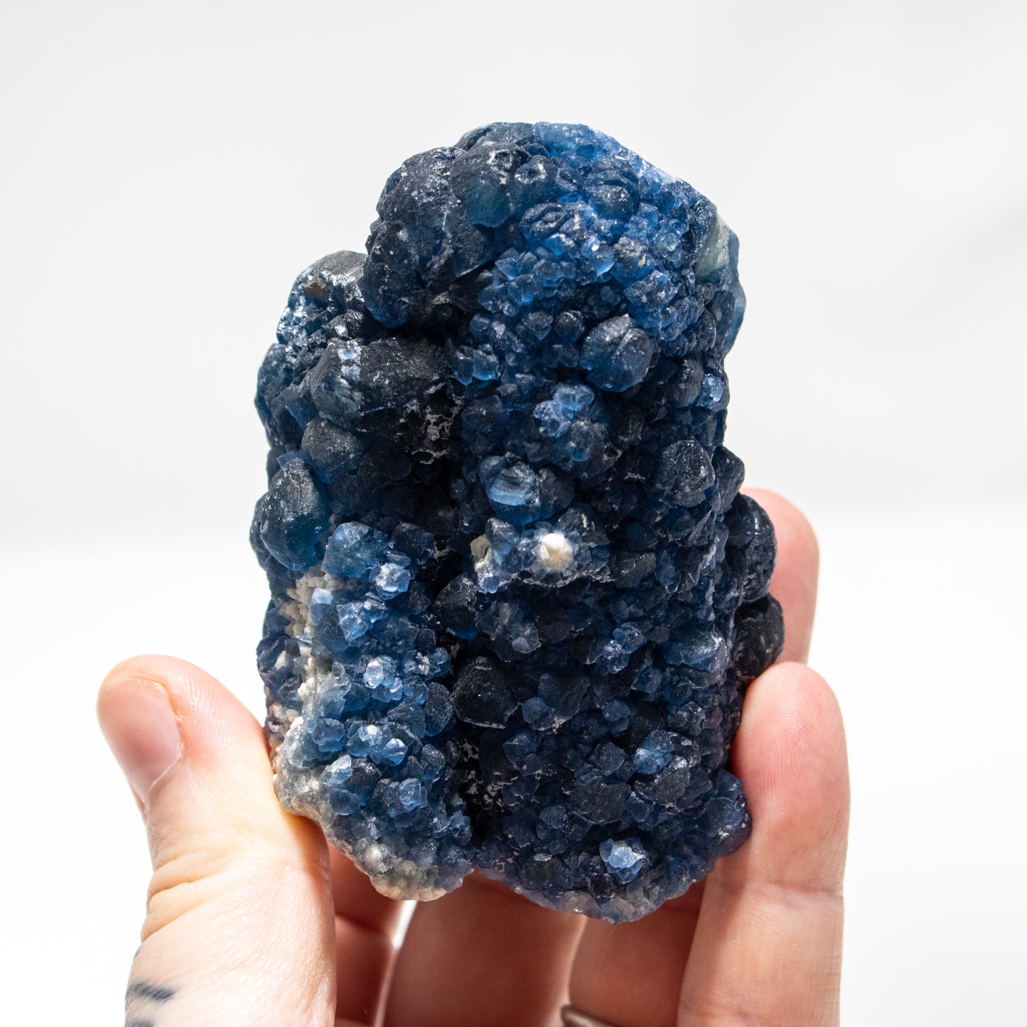 Hand holding a large blue crystal cluster against a white background