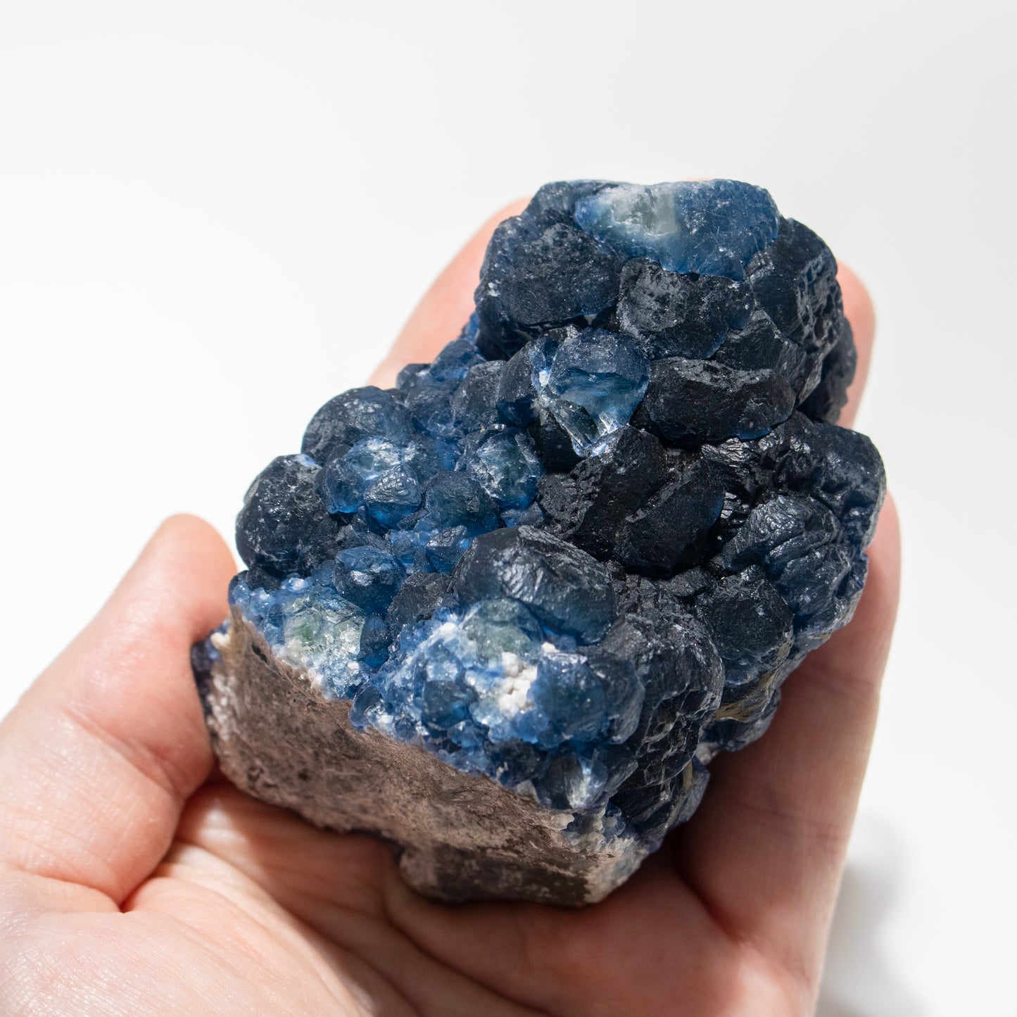 Hand holding a large blue crystal rock against a white background