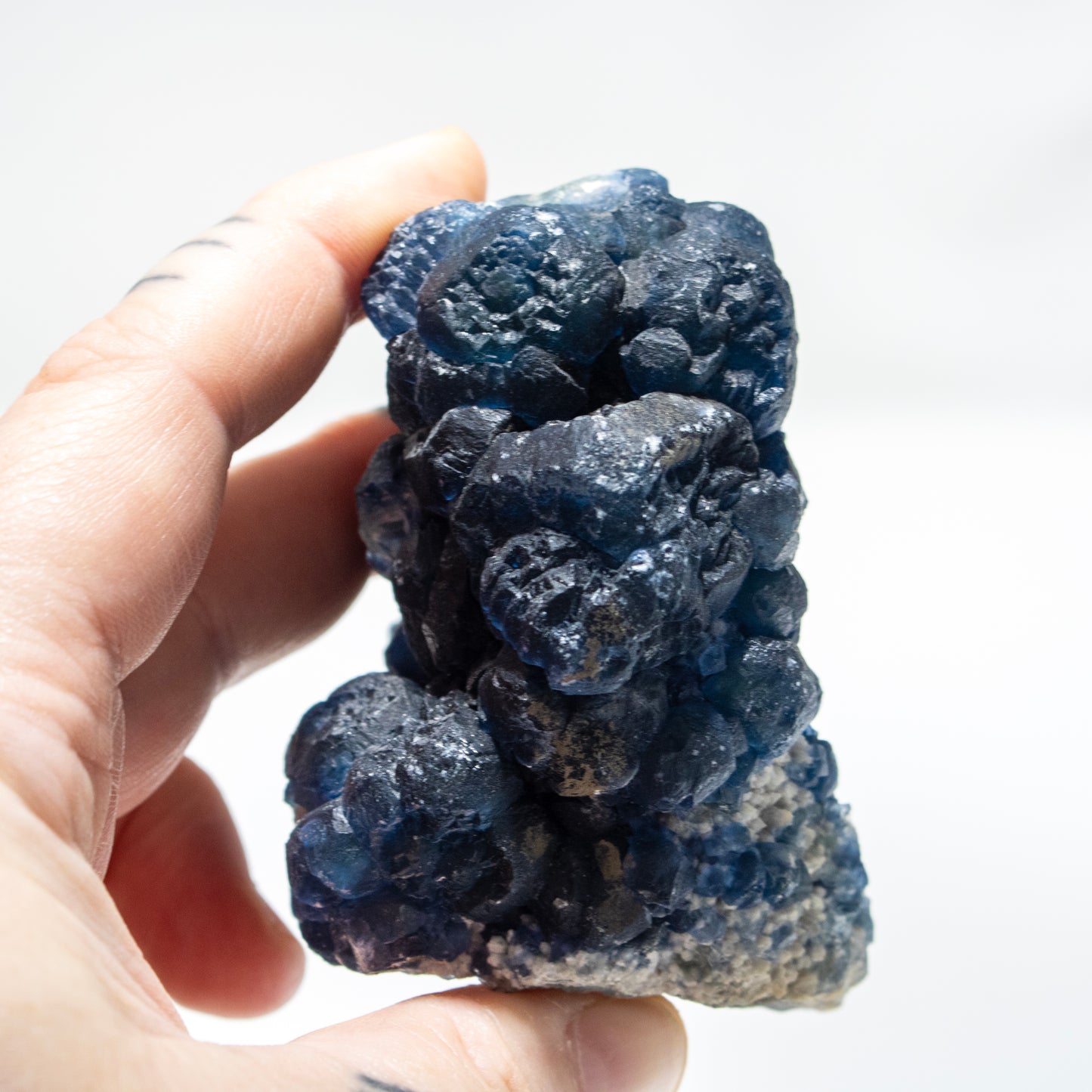 Hand holding a blue crystal rock against a white background