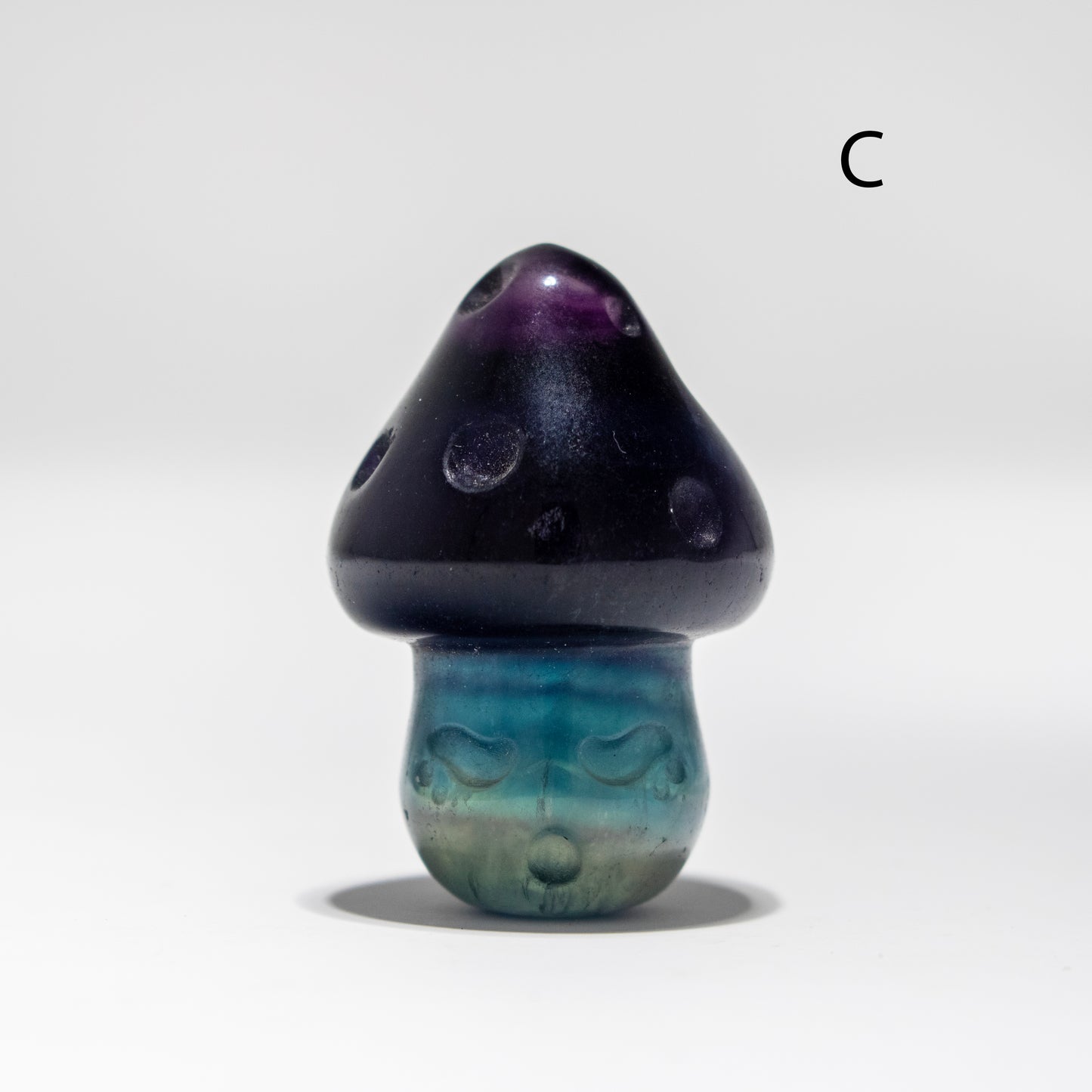 Fluorite mushroom with black cap and blue stem on a white background