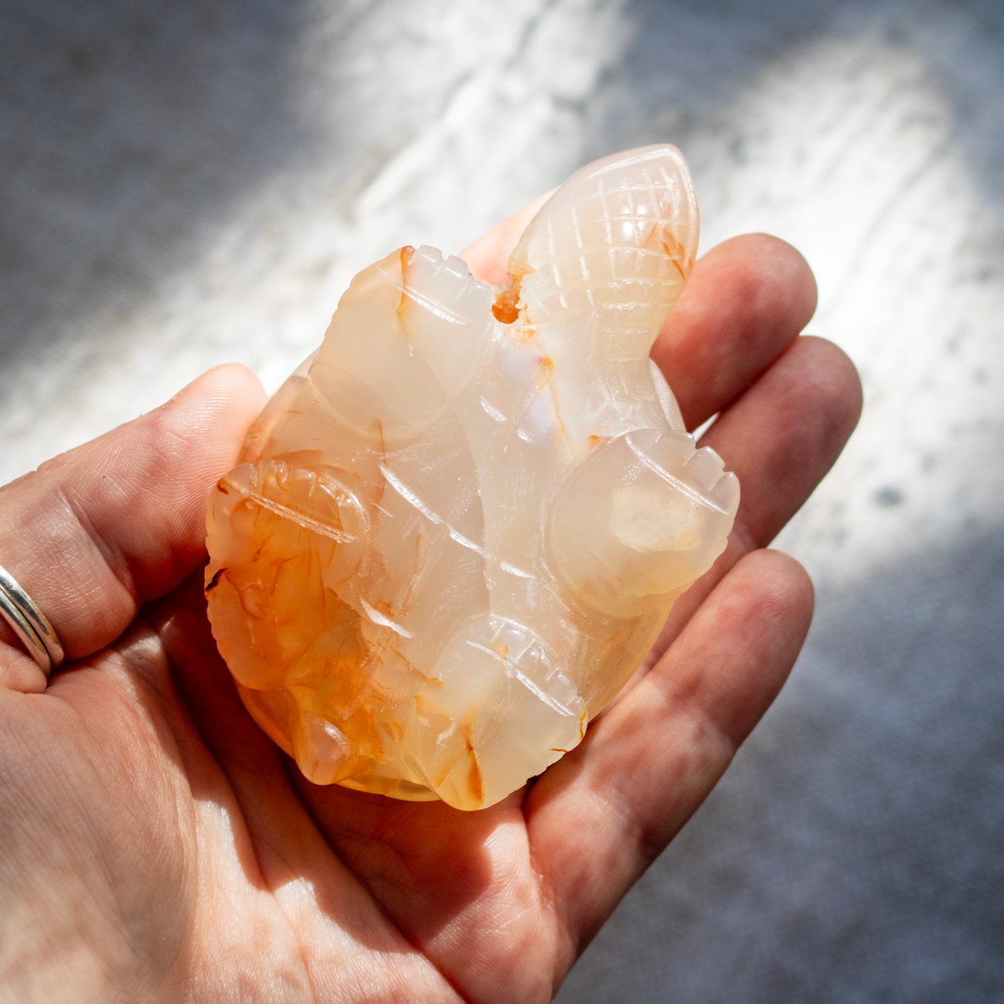 Hand holding a translucent stone sculpture against a neutral background