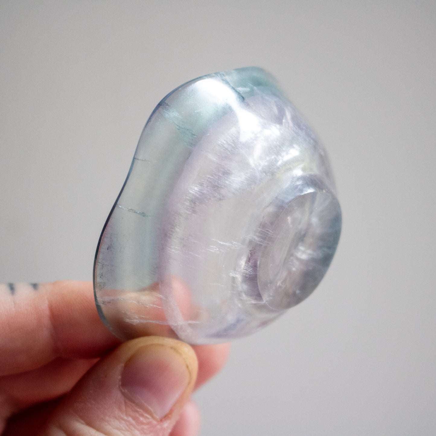 Clear stone held in a hand against a neutral background