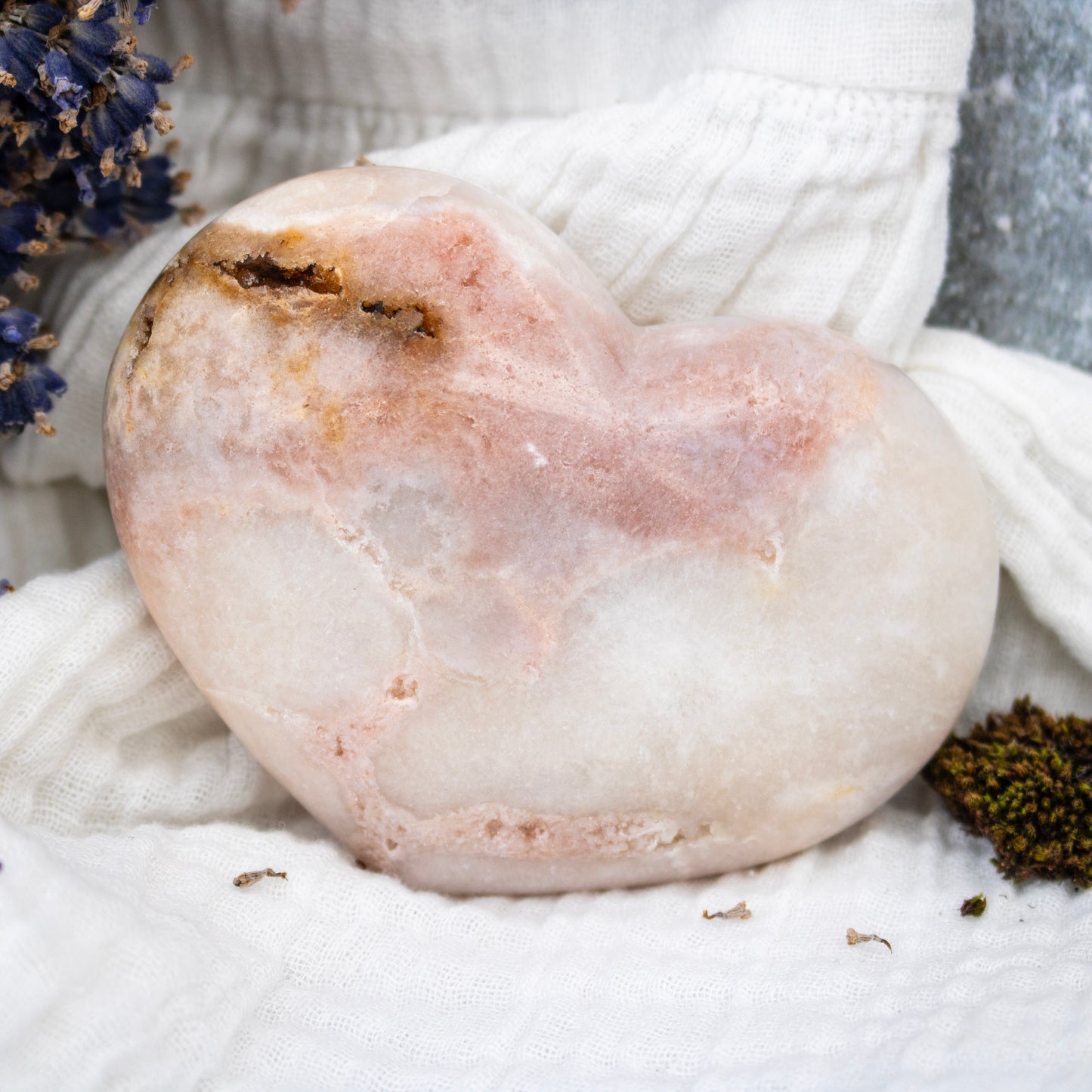 Close-up of a pinkish stone with natural textures on a white fabric background