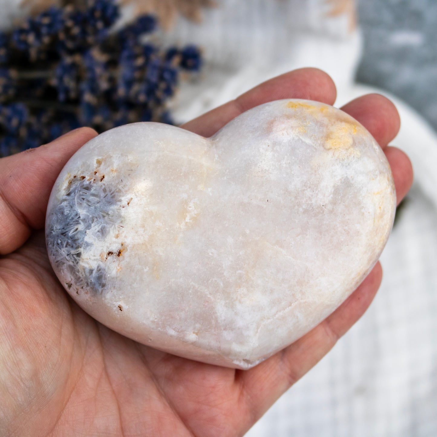 Heart-shaped stone held in a hand with a blurred background