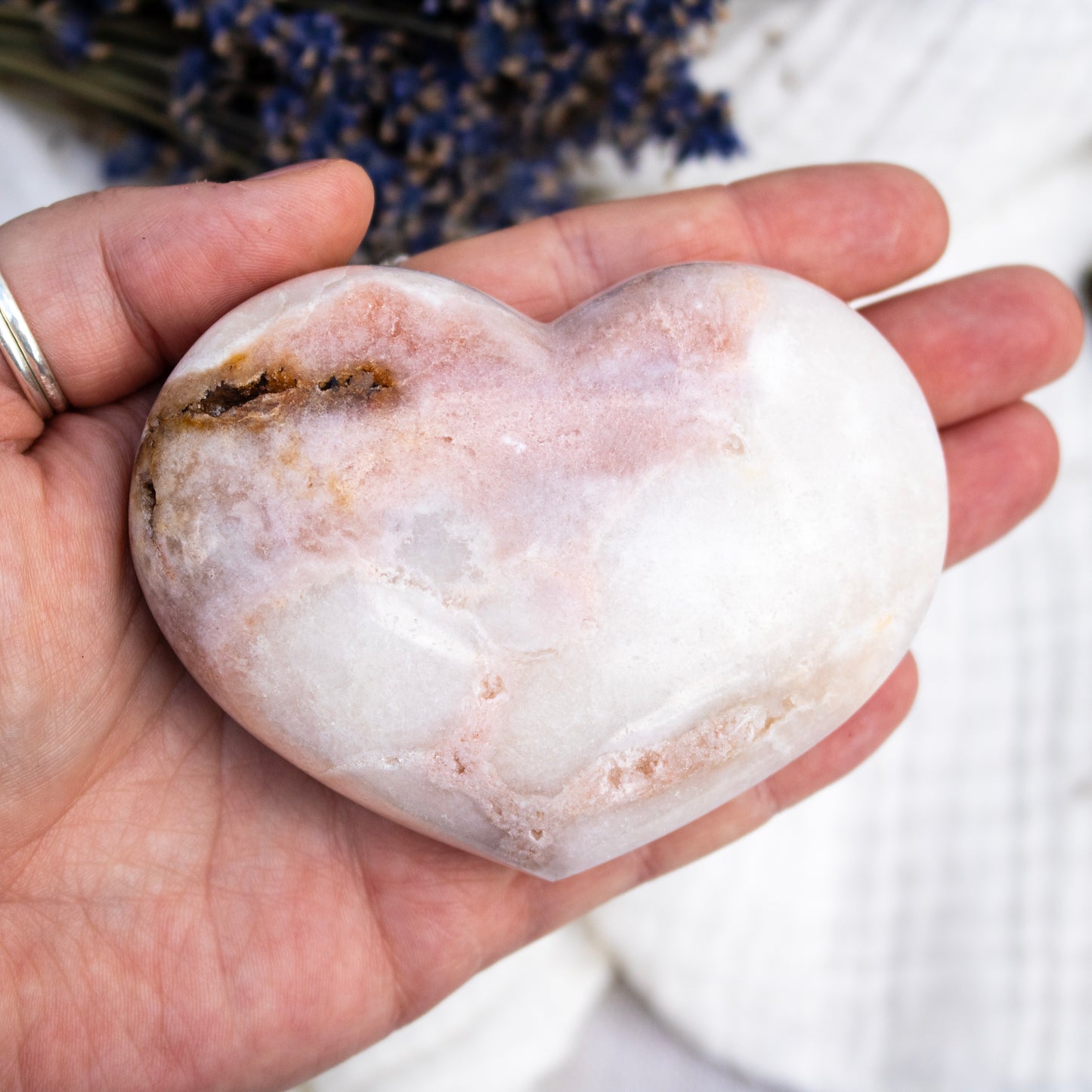 Heart-shaped stone held in a hand with a blurred background