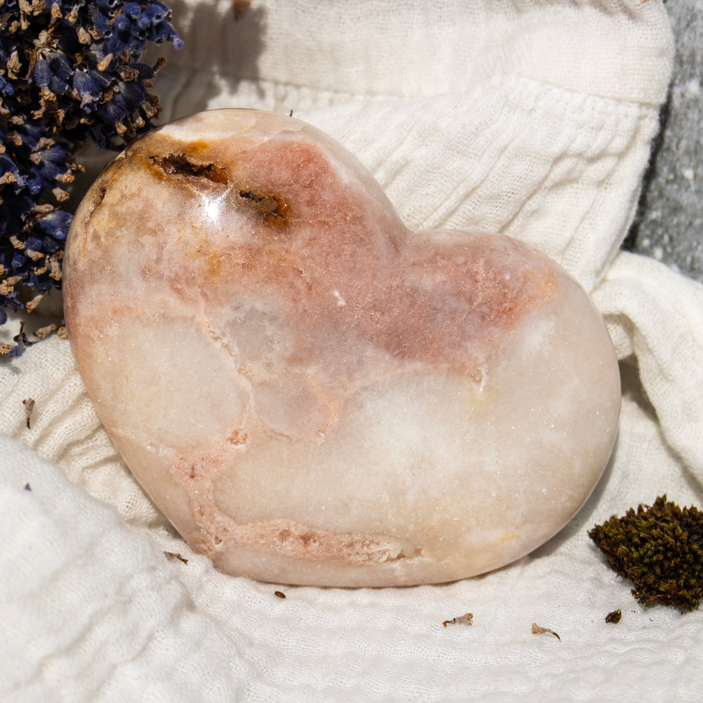Heart-shaped stone on a textured surface with dried lavender and moss