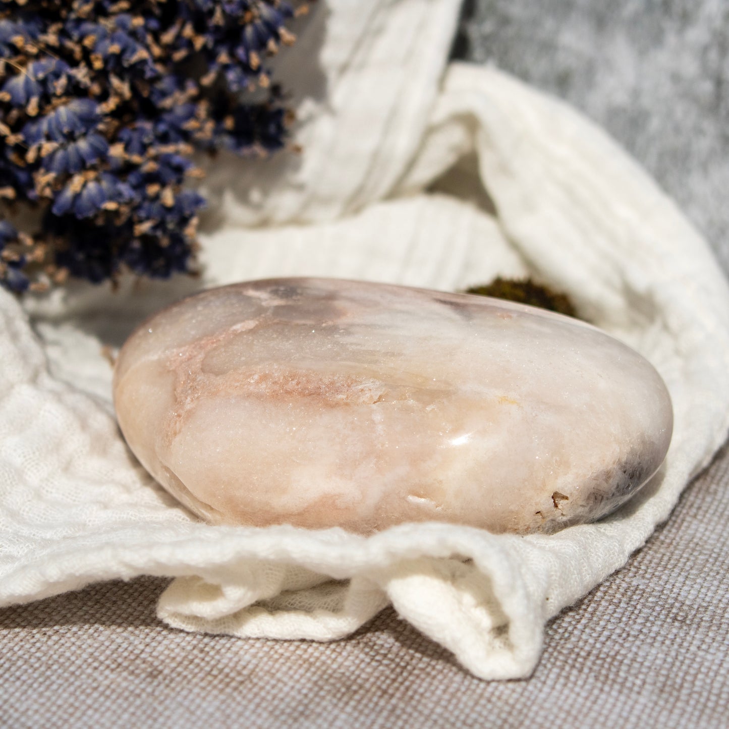 Stone on a white cloth with lavender flowers in the background