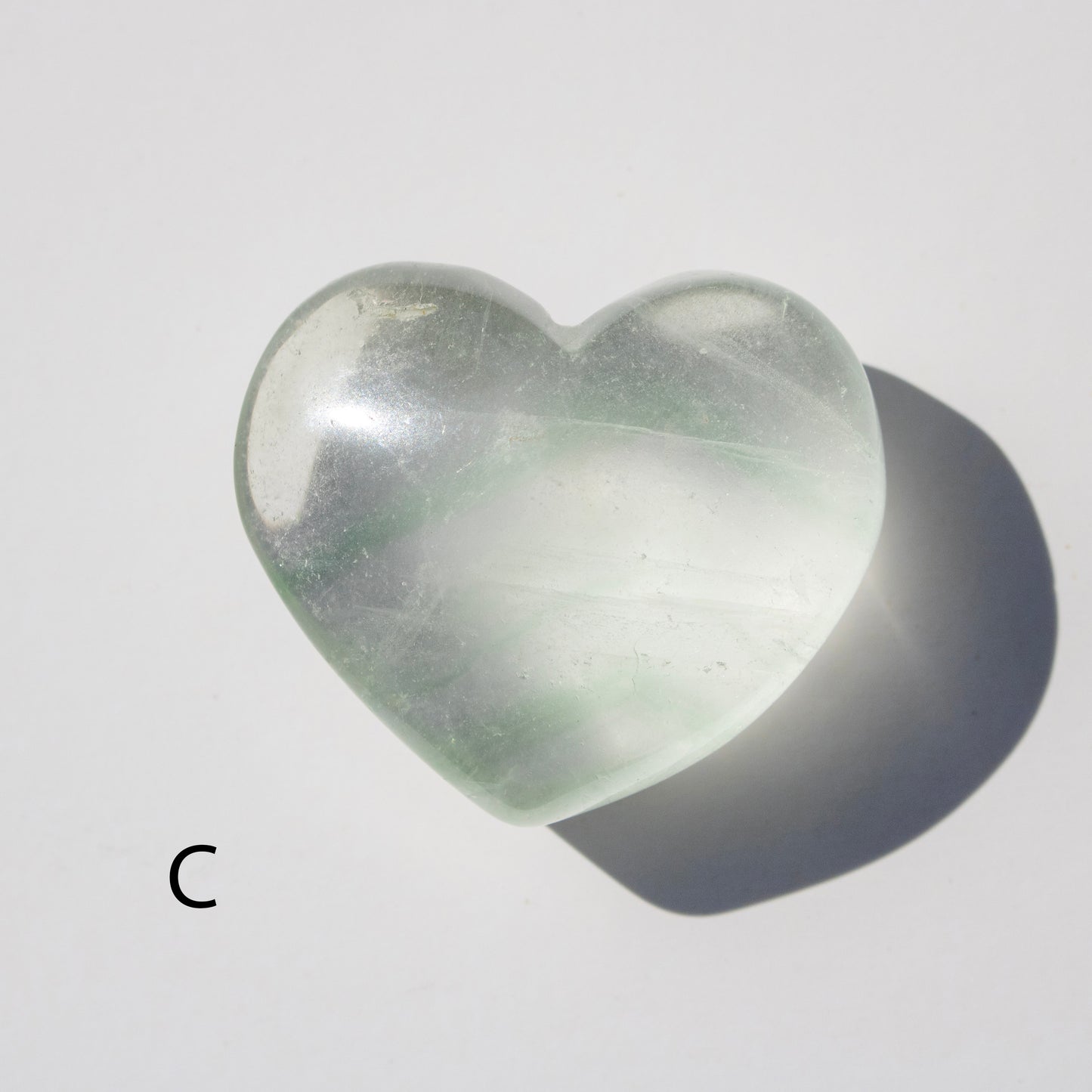 Heart-shaped green stone on a light gray background