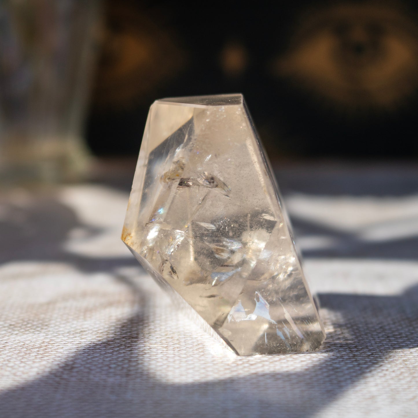 Clear crystal pyramid on a textured surface with a blurred natural background