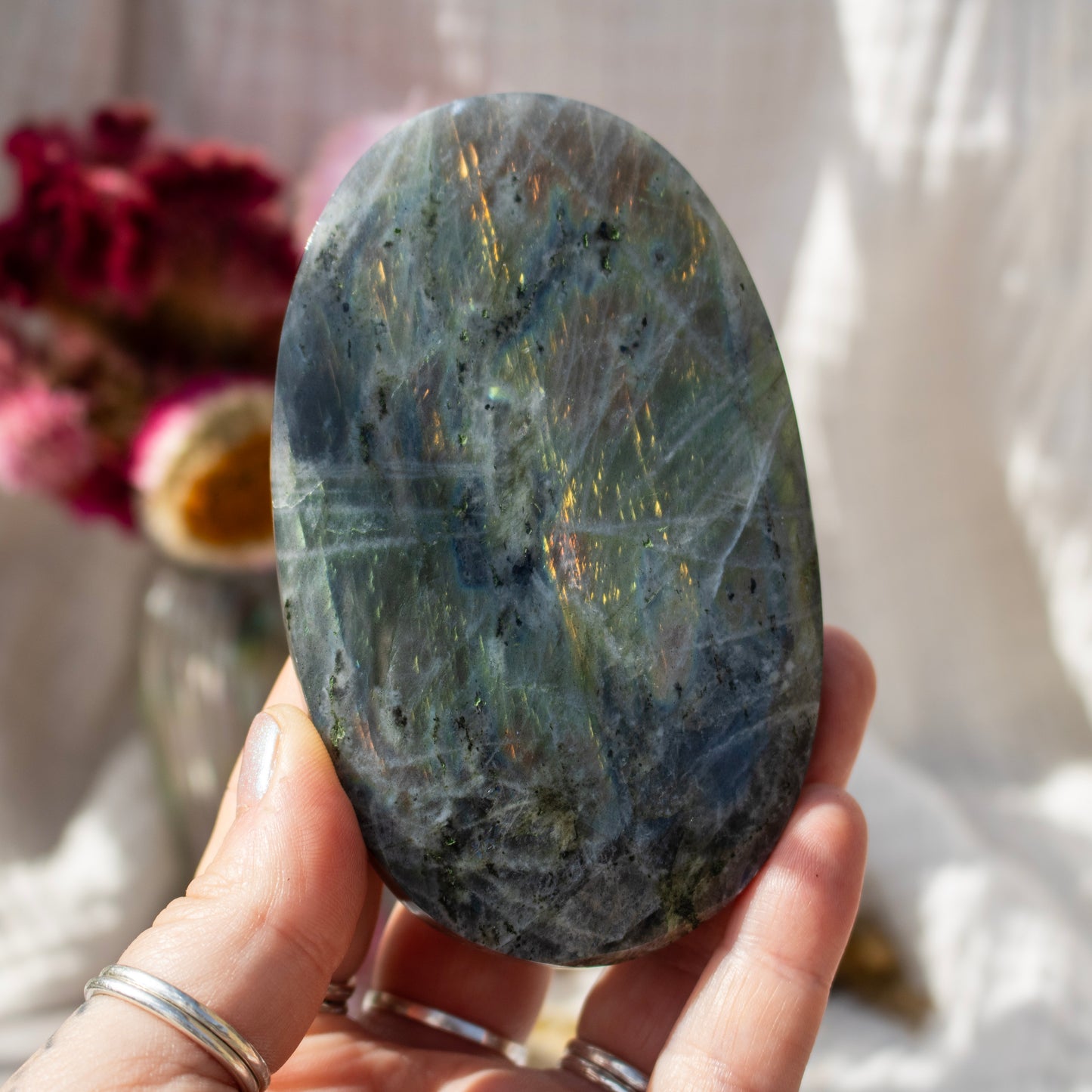 Hand holding a large labradorite stone with a blurred background