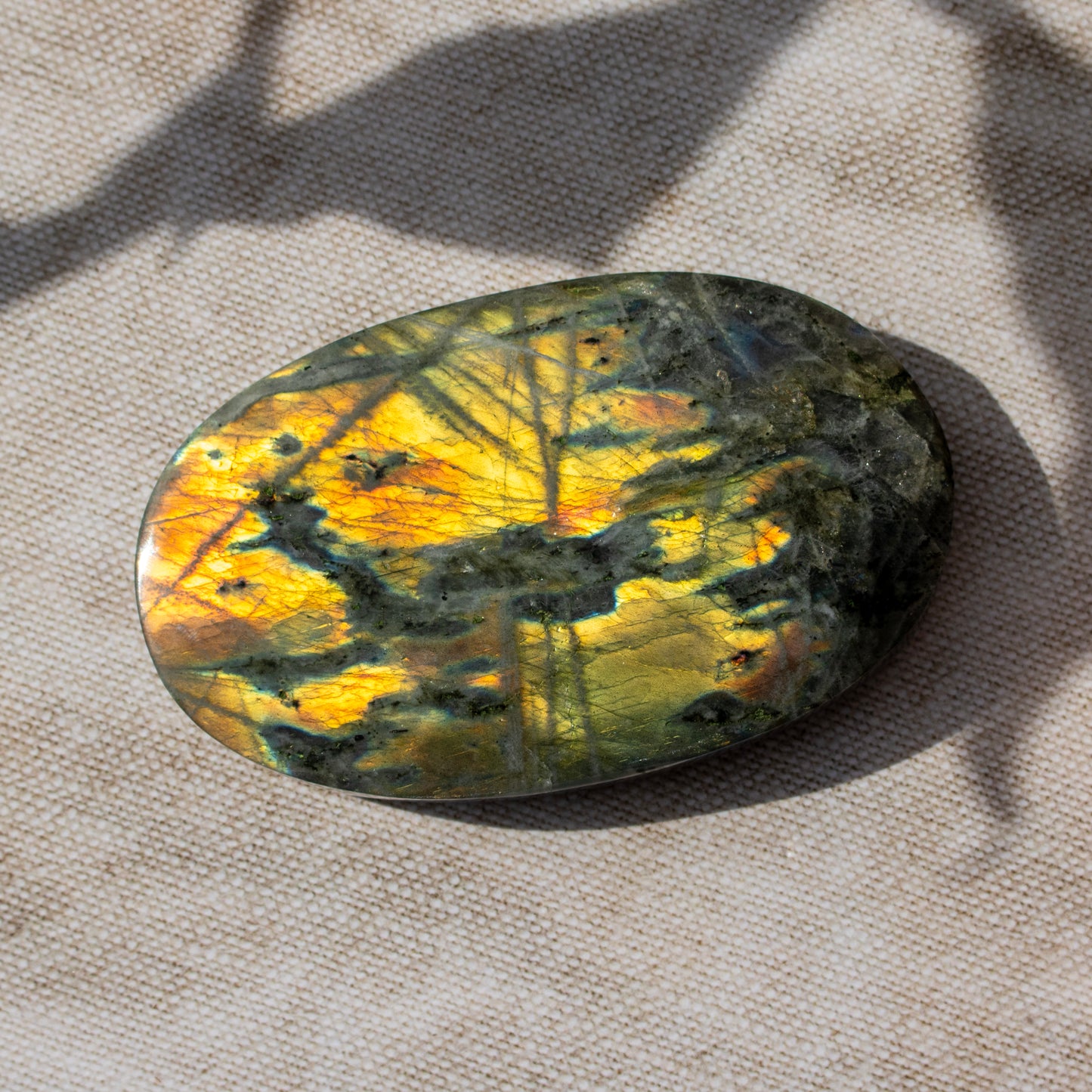 Oval-shaped labradorite stone on a textured fabric background