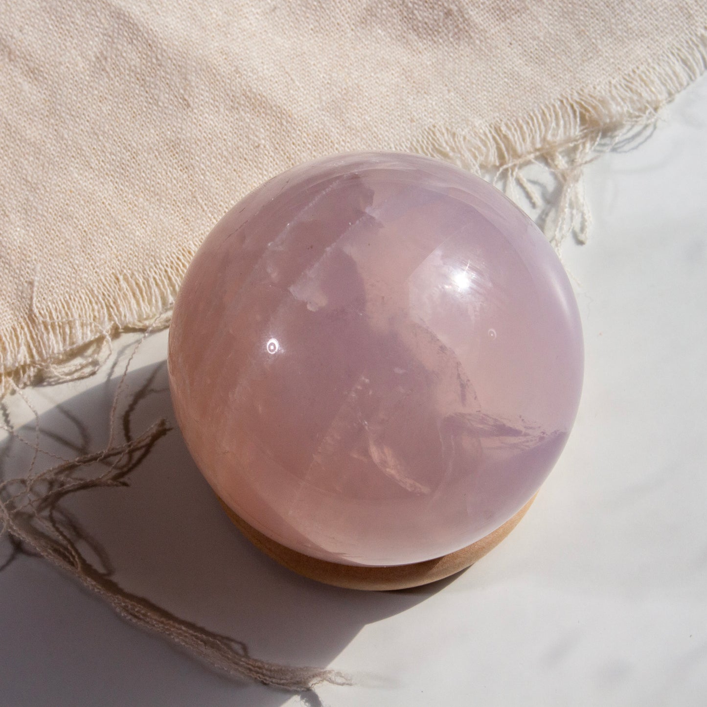 Rose quartz crystal sphere on a textured surface