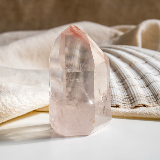 Clear crystal on a white surface with a beige shell in the background