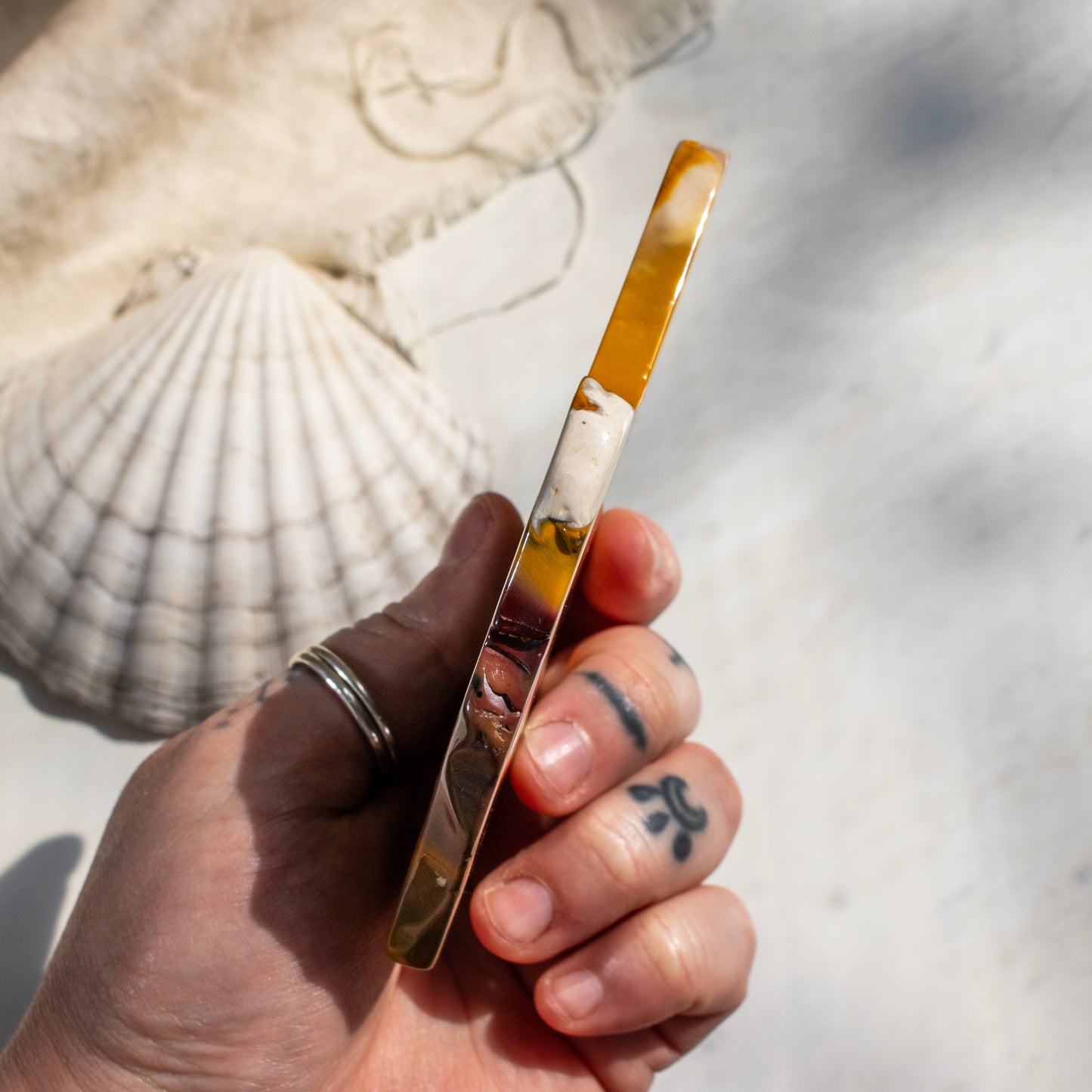 Hand holding a crystal slice with a shell in the background