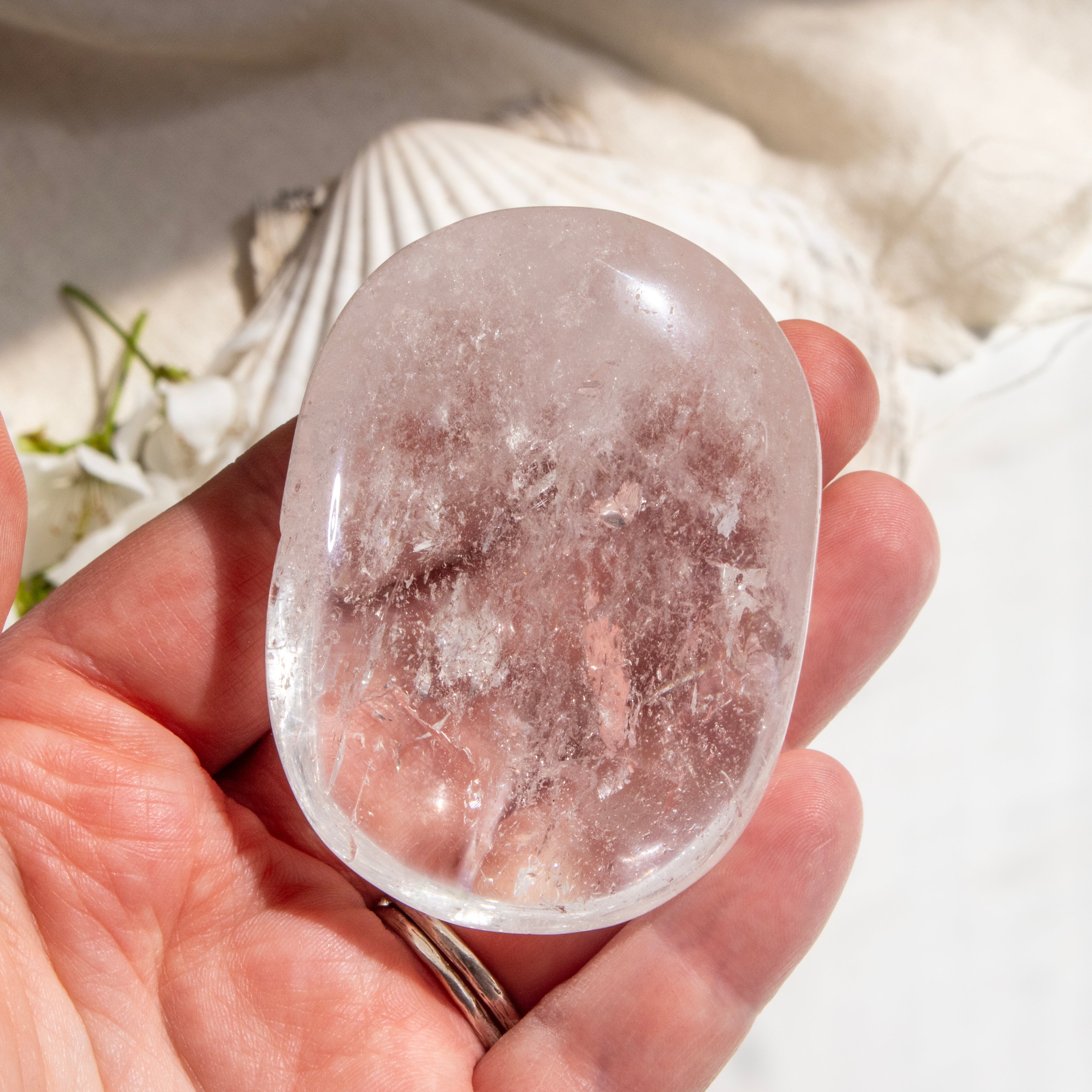 Clear crystal stone held in a hand with a natural background