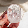 Clear crystal held in a hand against a natural background