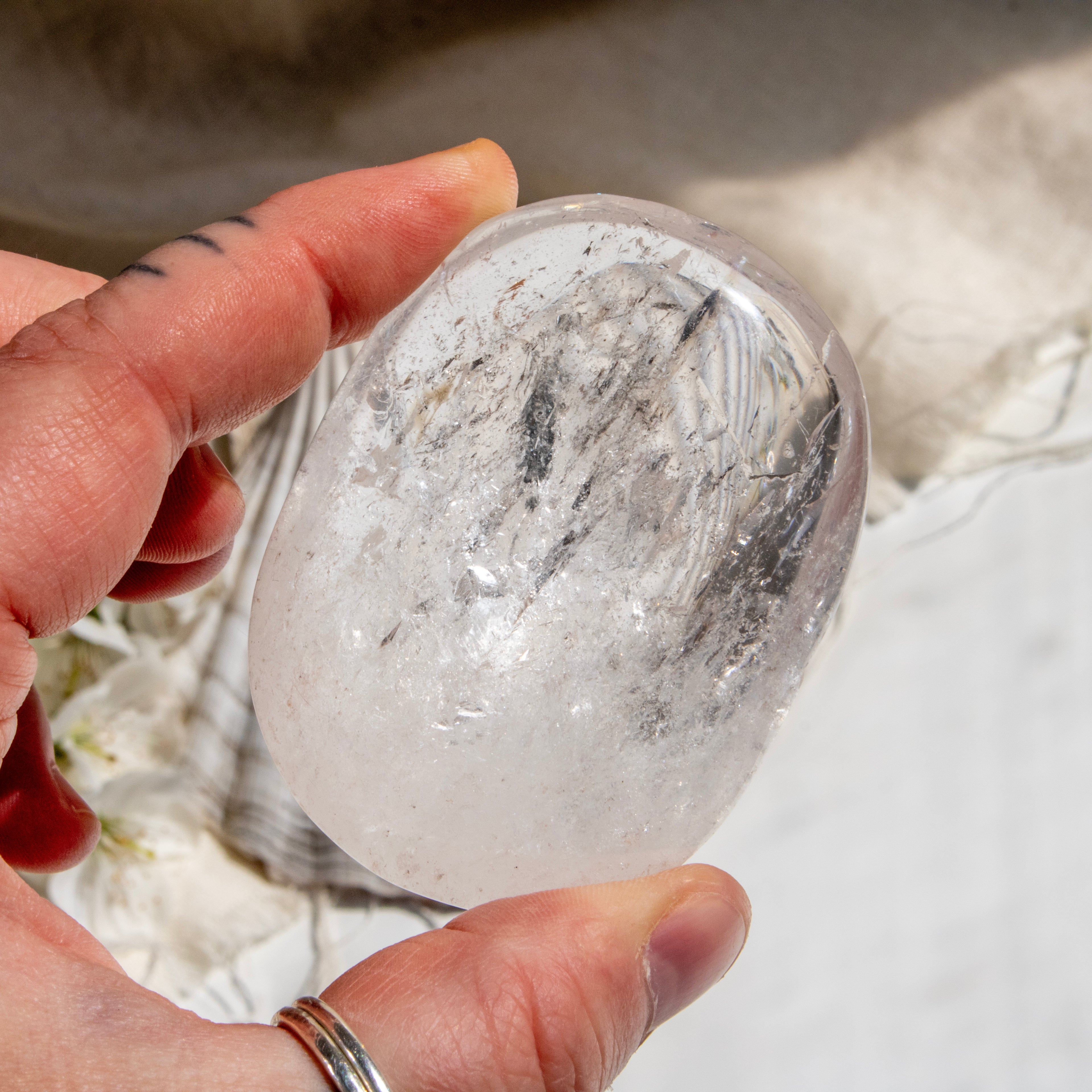 Person holding a clear crystal rock with a blurred natural background