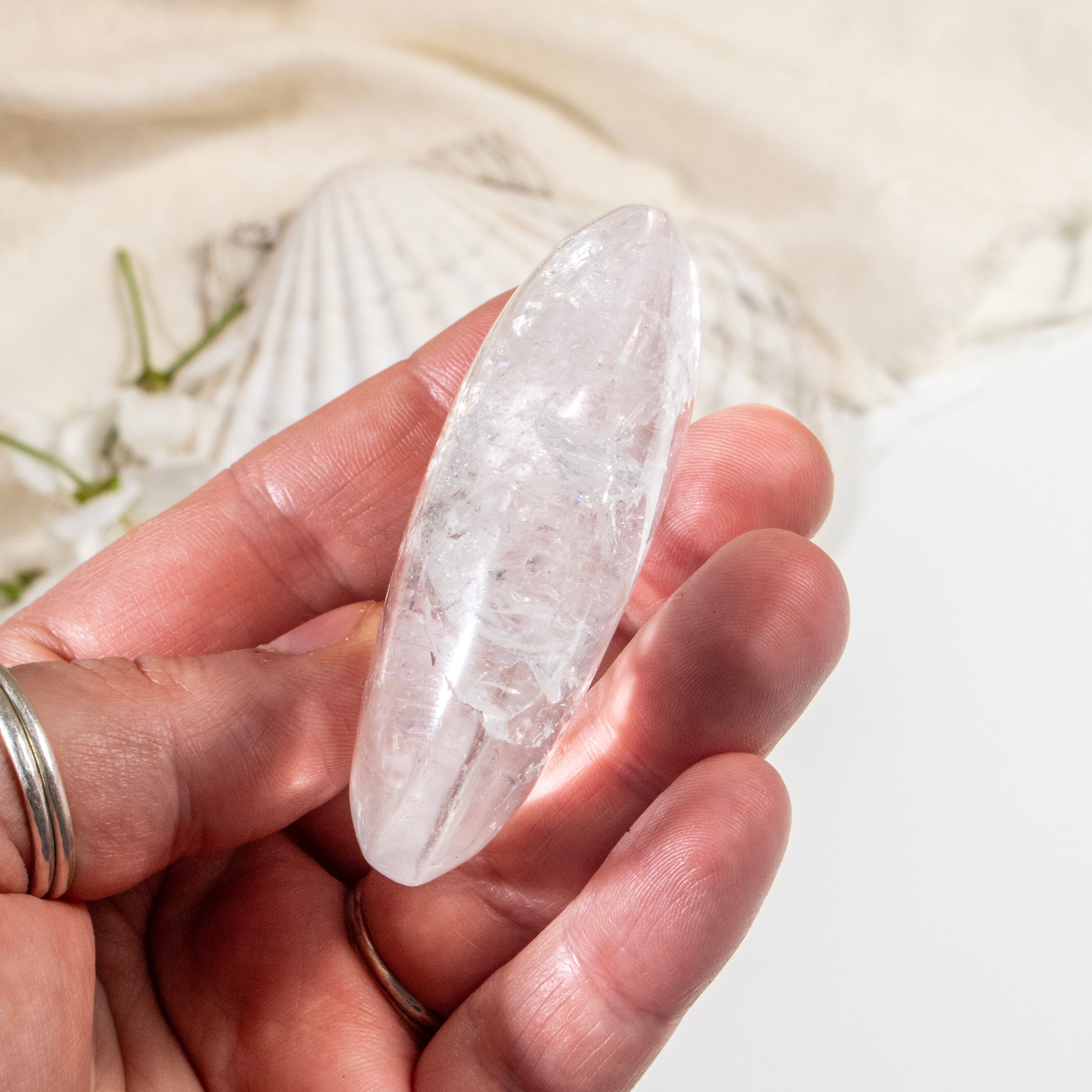 Hand holding a clear crystal stone with a soft focus background
