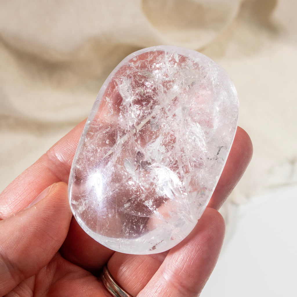 Clear crystal held in a hand against a neutral background