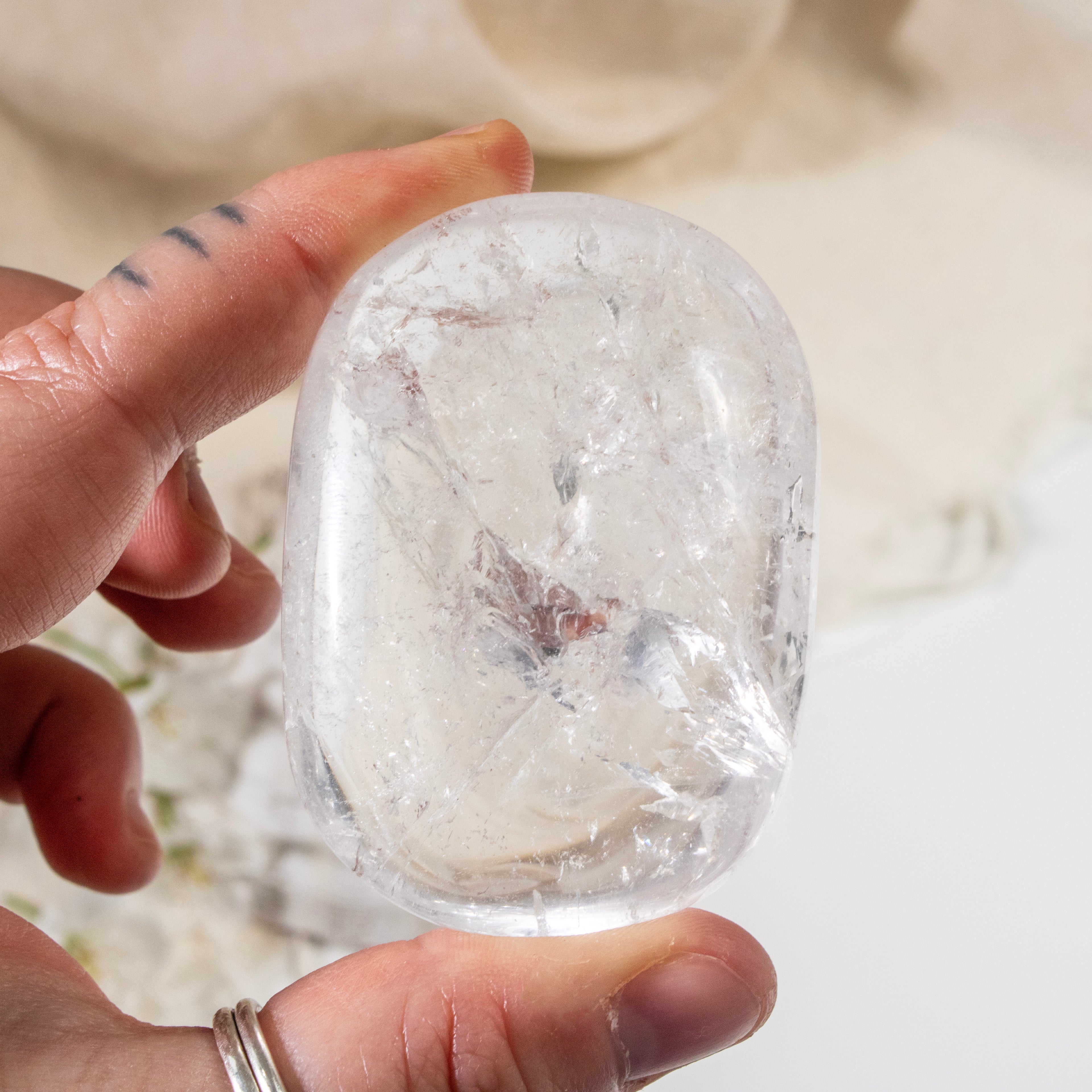 Clear crystal held by a hand against a neutral background