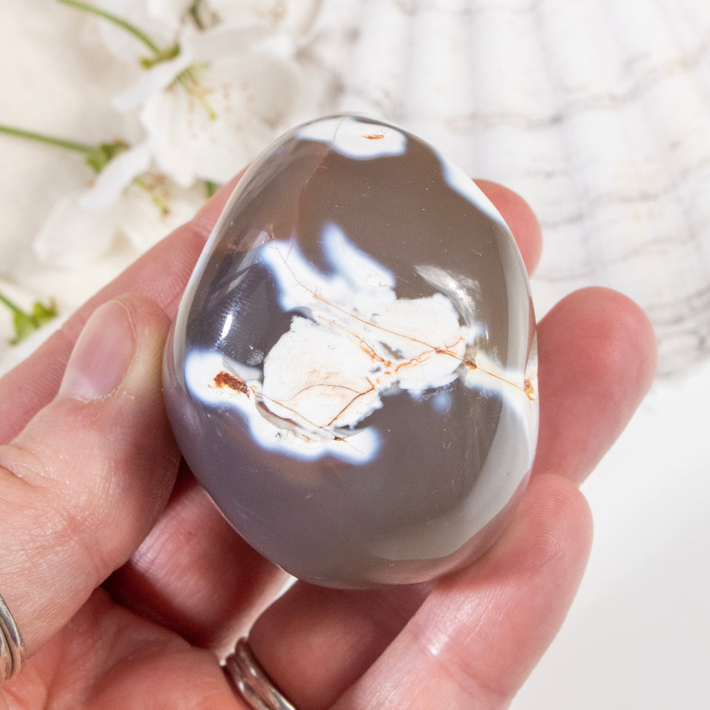 Hand holding a crystal with intricate patterns on a blurred natural background
