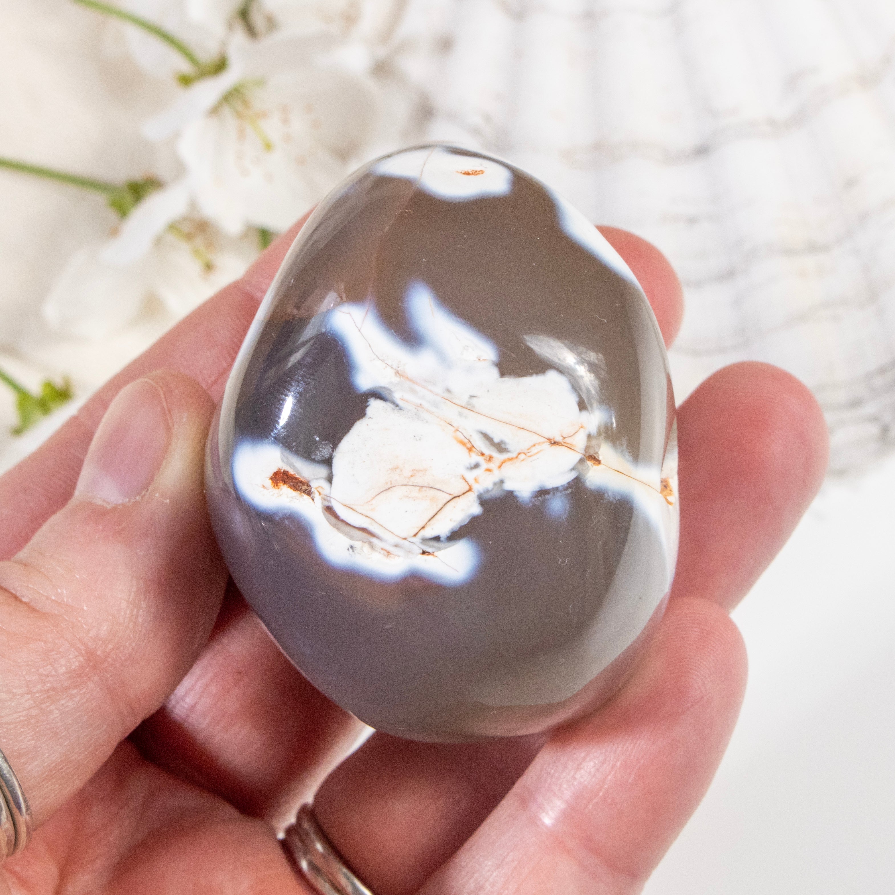 Hand holding a crystal with intricate patterns on a blurred natural background