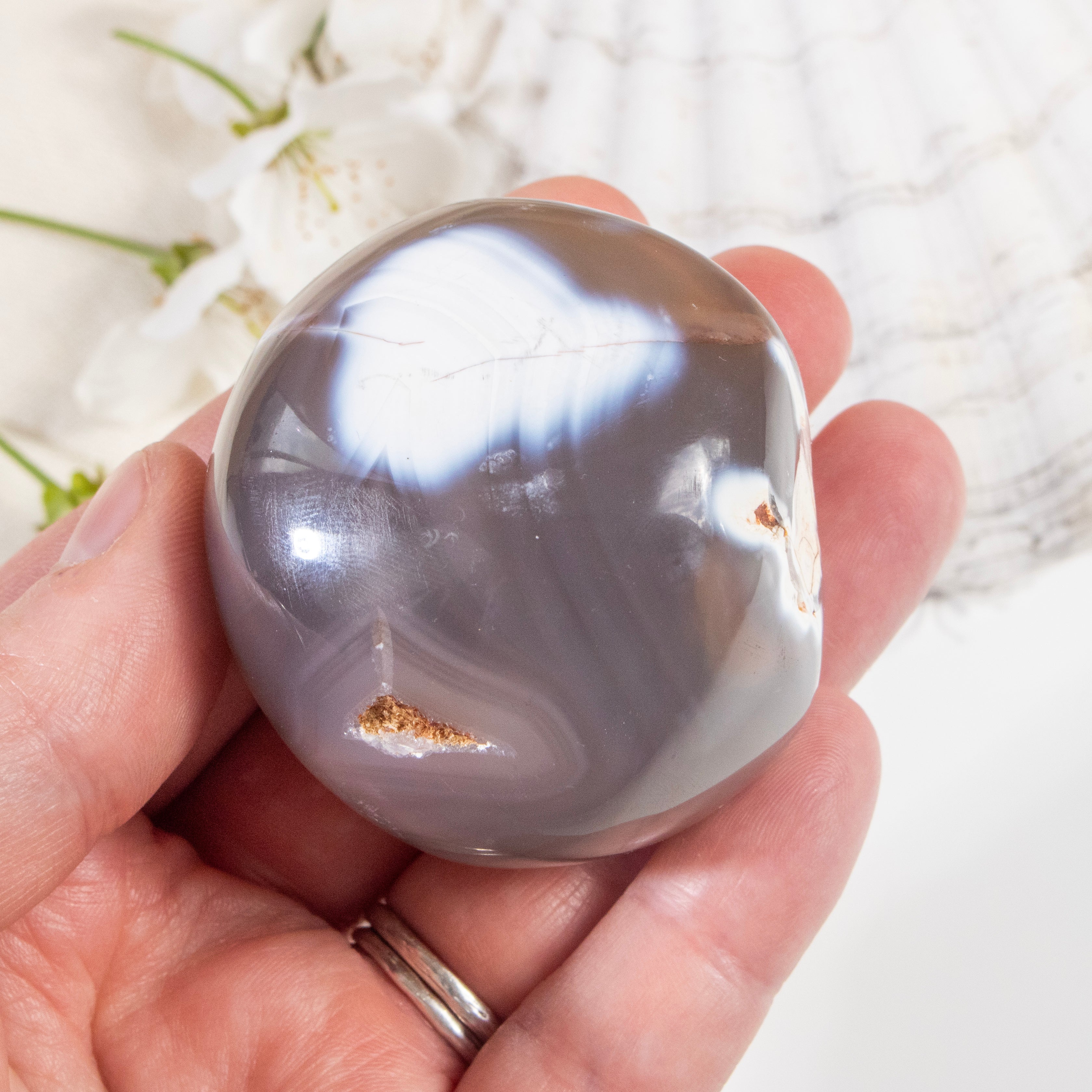 Hand holding a large crystal ball with a white floral background