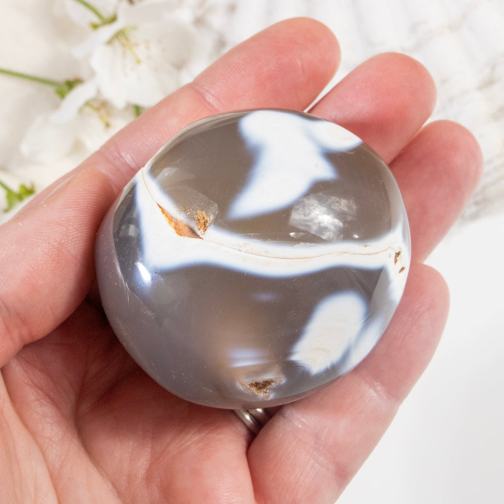 Hand holding a marbled stone with a white background