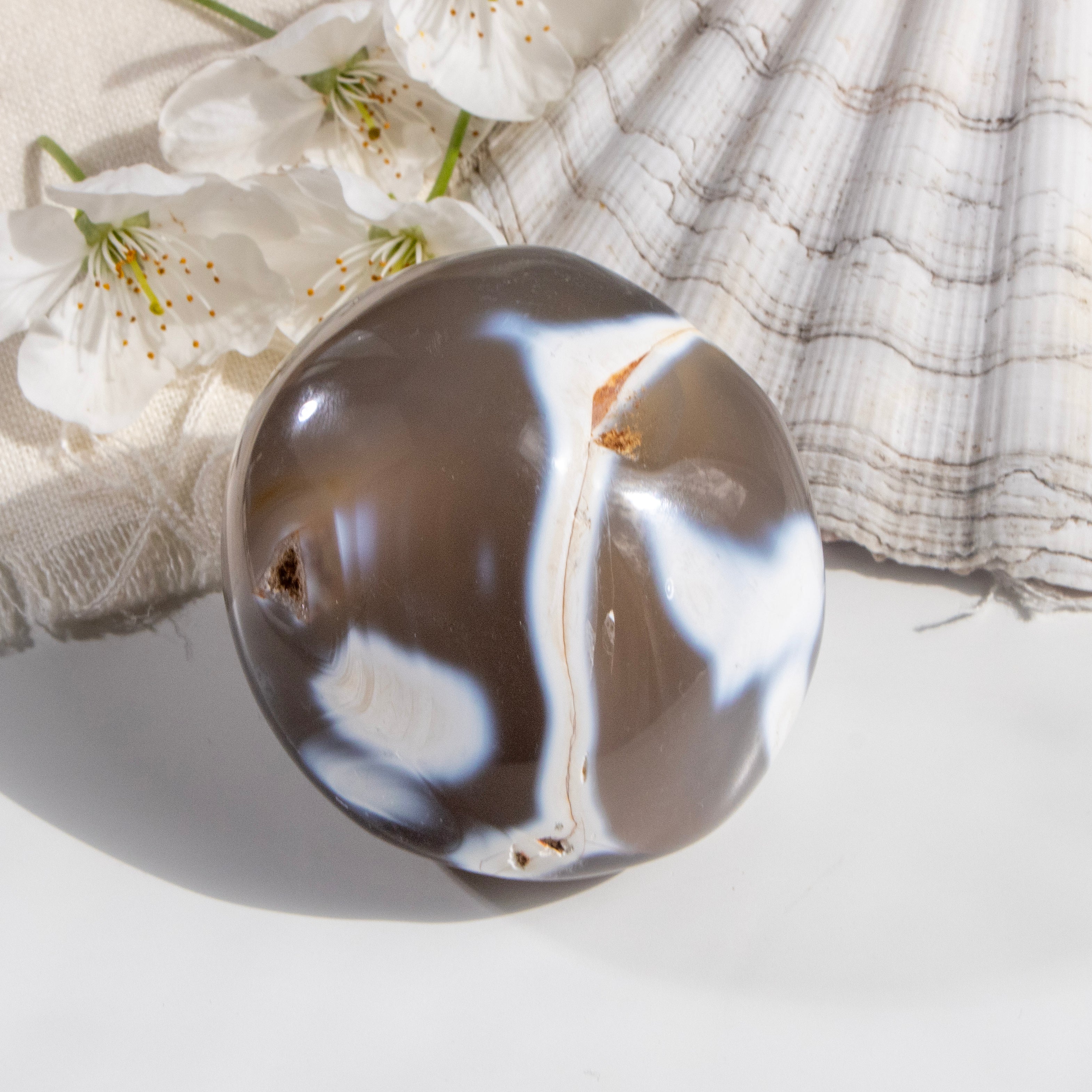 Decorative stone with white and brown patterns on a light background with flowers and fabric.