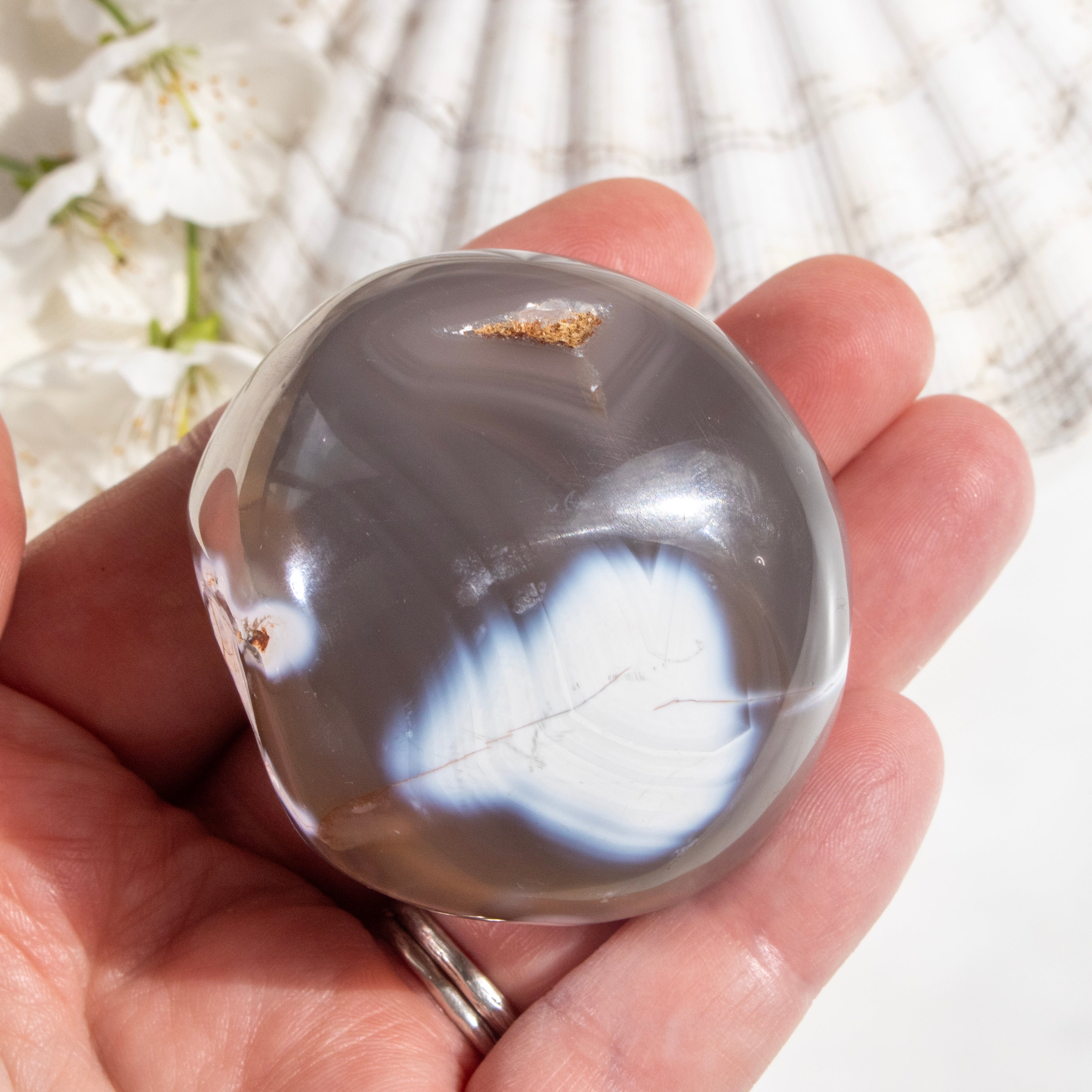 Hand holding a polished agate stone with a natural background