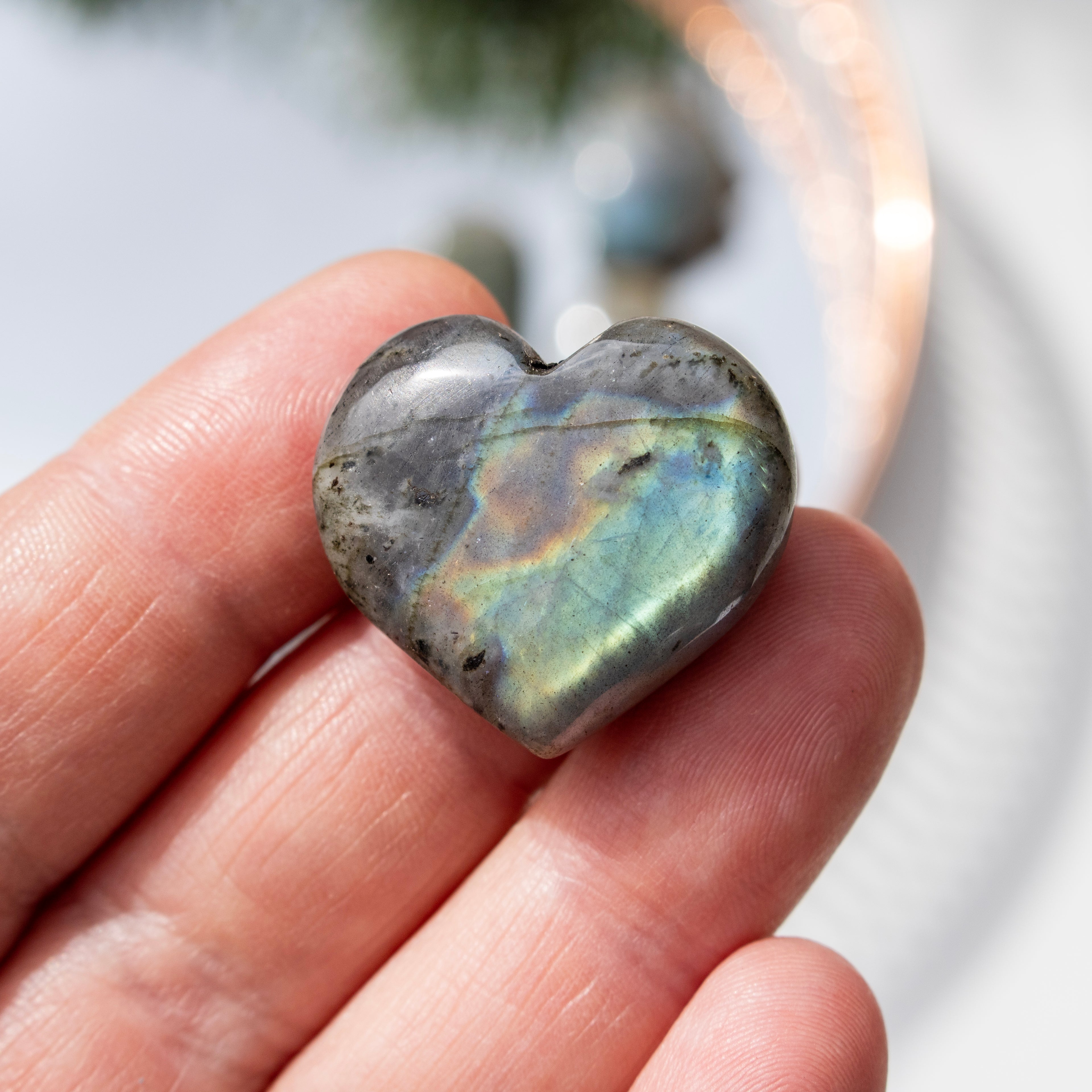 Heart-shaped stone held in a hand with a blurred background