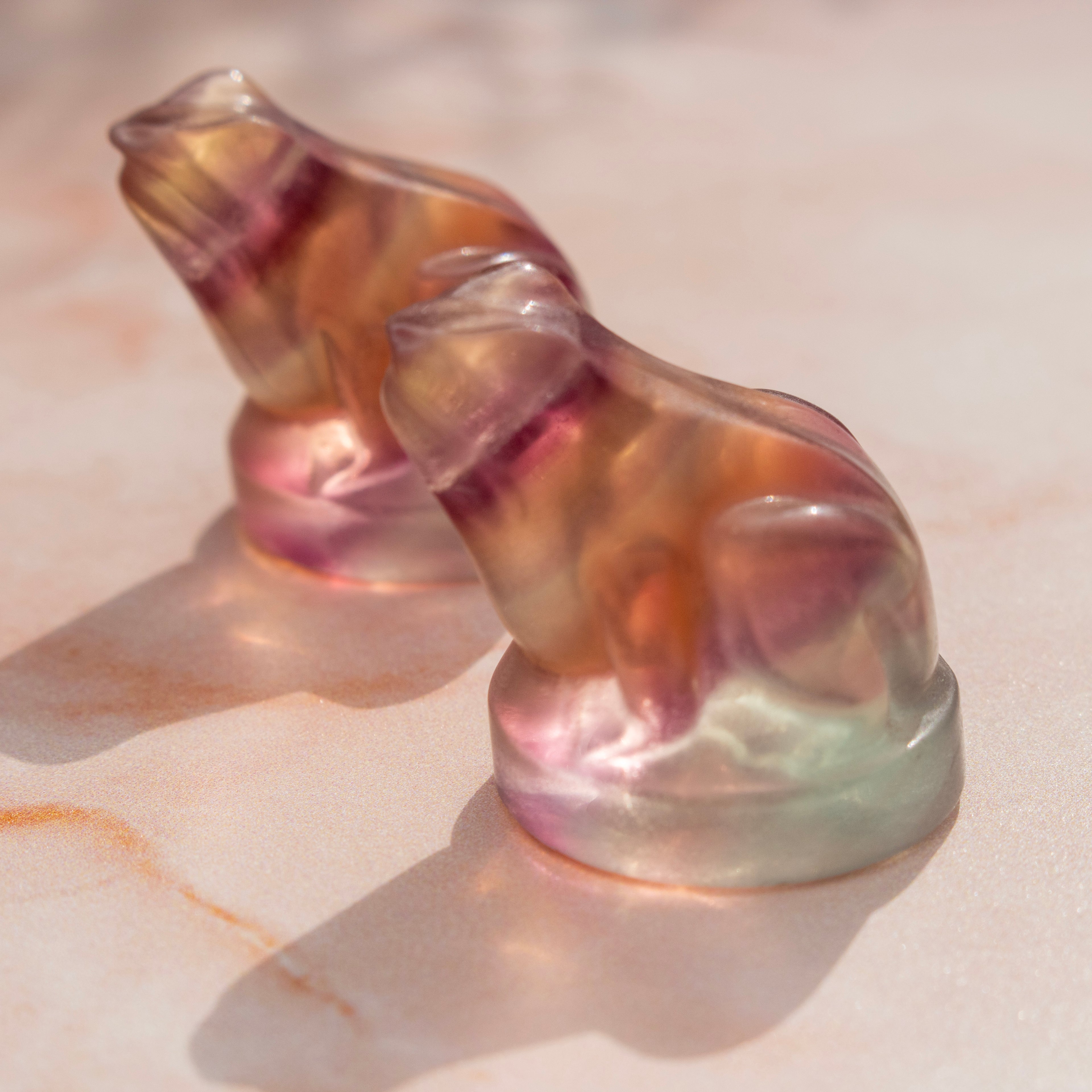 Translucent fluorite frog figurine on a textured surface