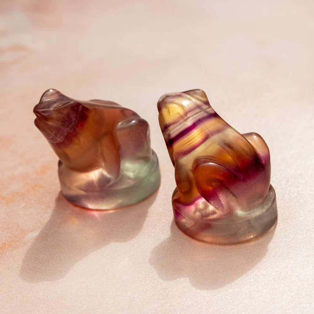 Two multicolored crystal sculptures on a beige surface