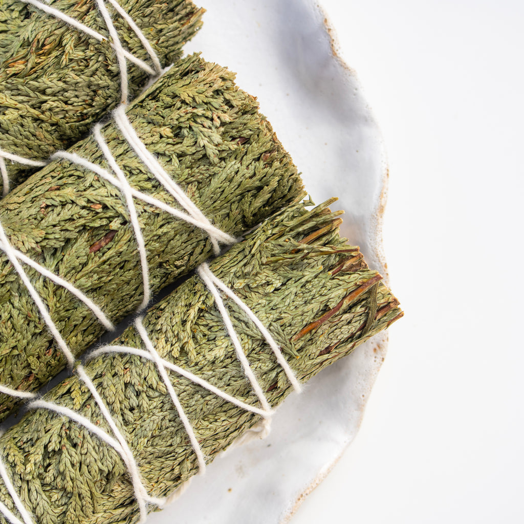 Green cedar leaves tied with white string on a marble surface