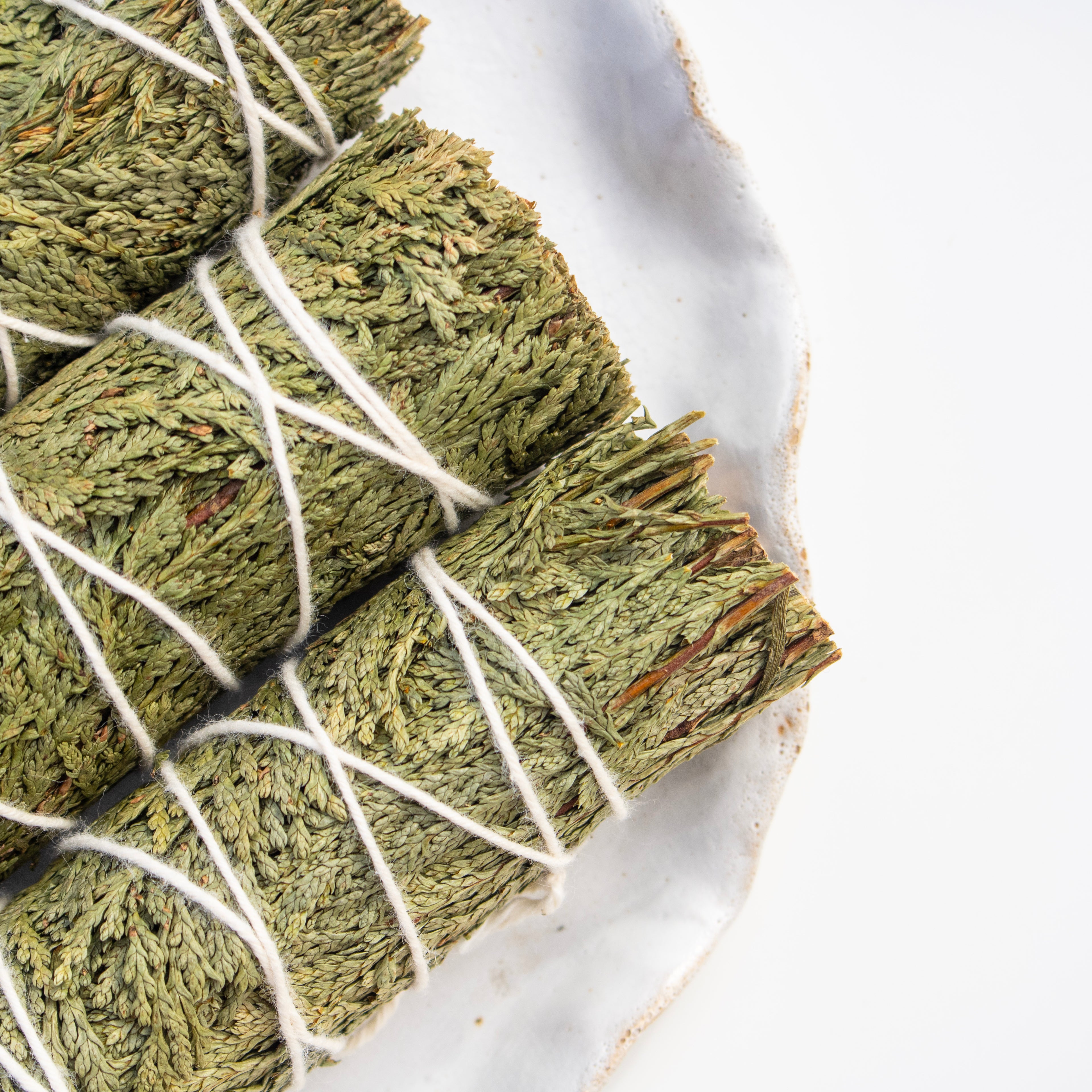 Green cedar leaves tied with white string on a marble surface