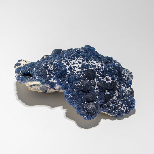 Blue and white mineral specimen on a light gray background