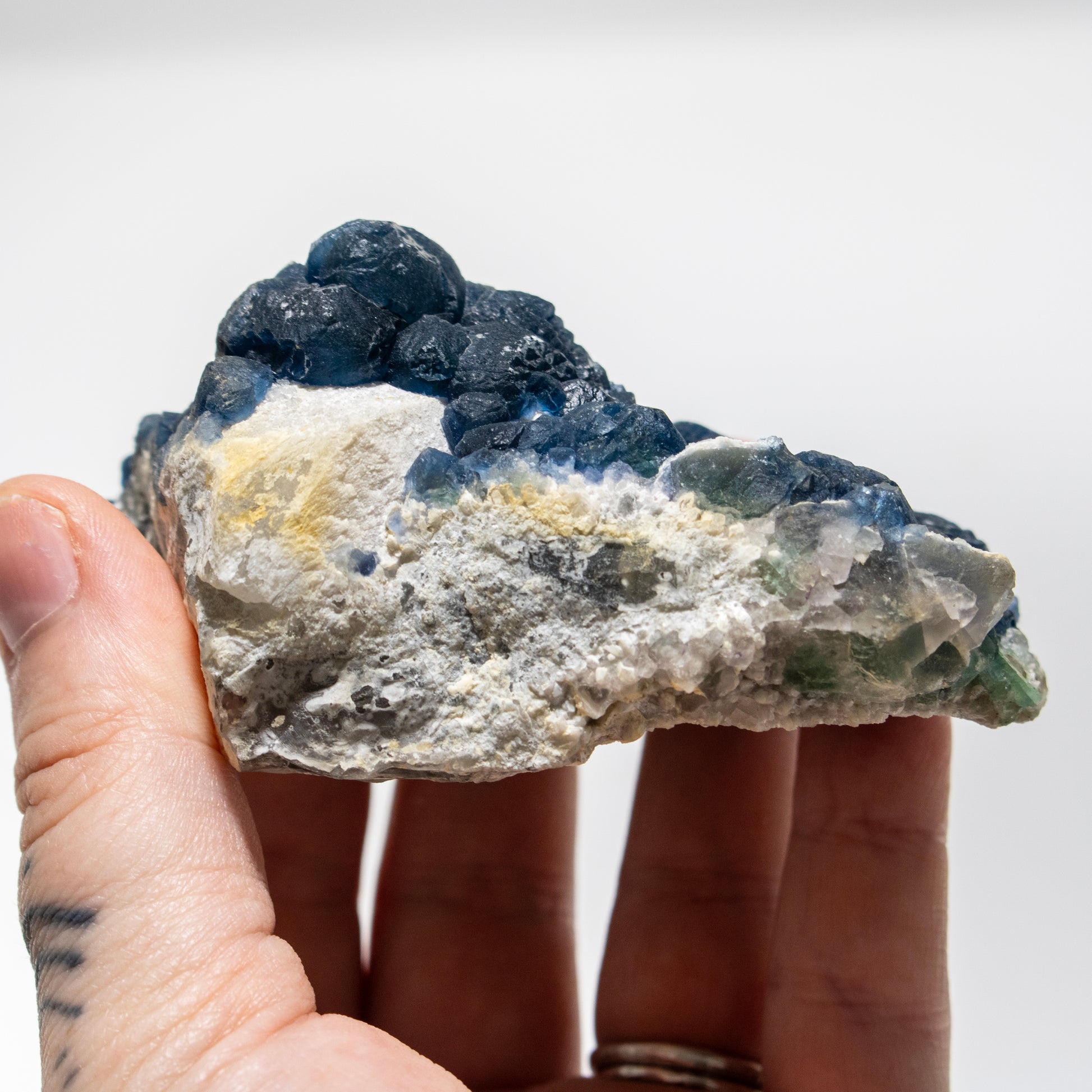 Hand holding a rough mineral stone against a white background