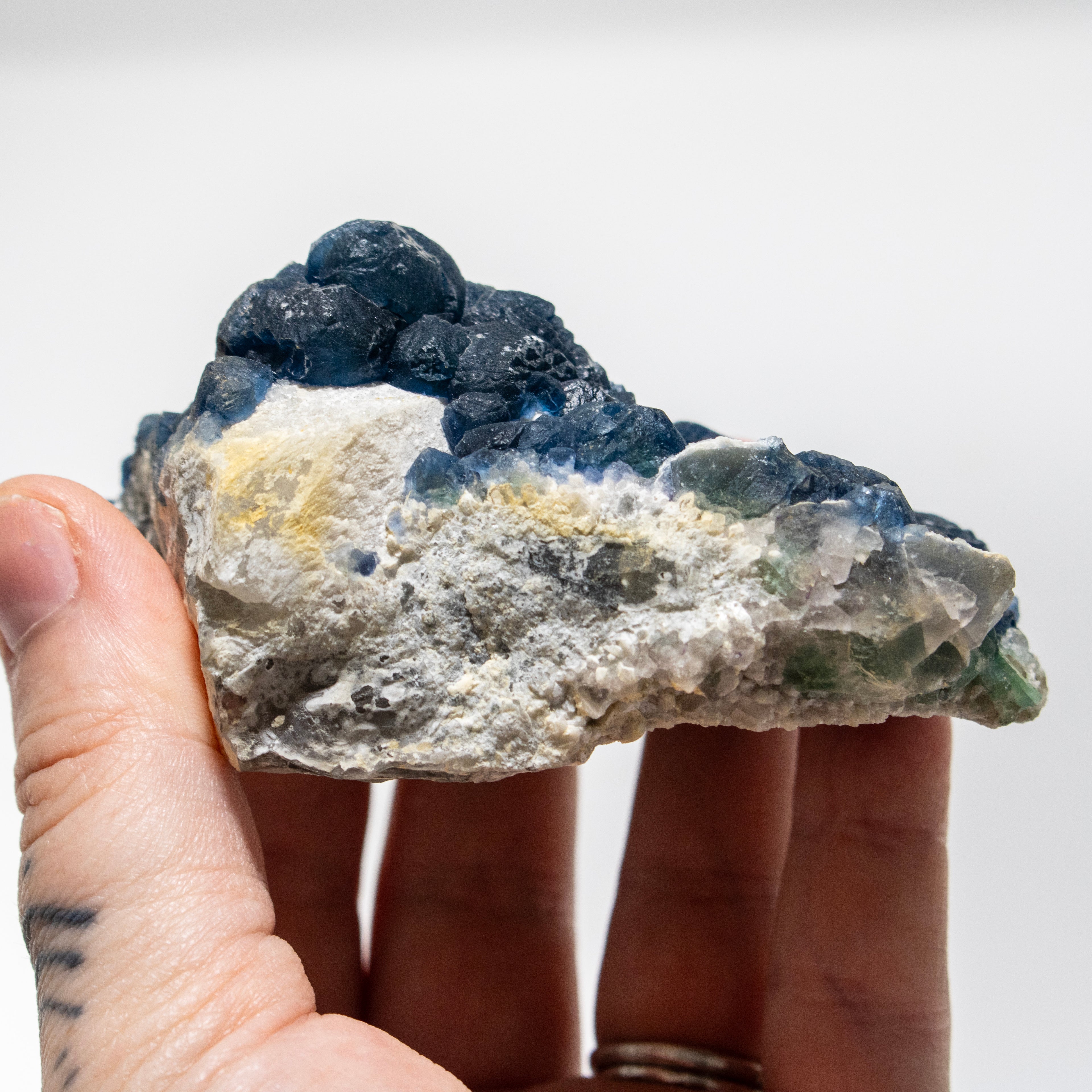 Hand holding a rough mineral stone against a white background