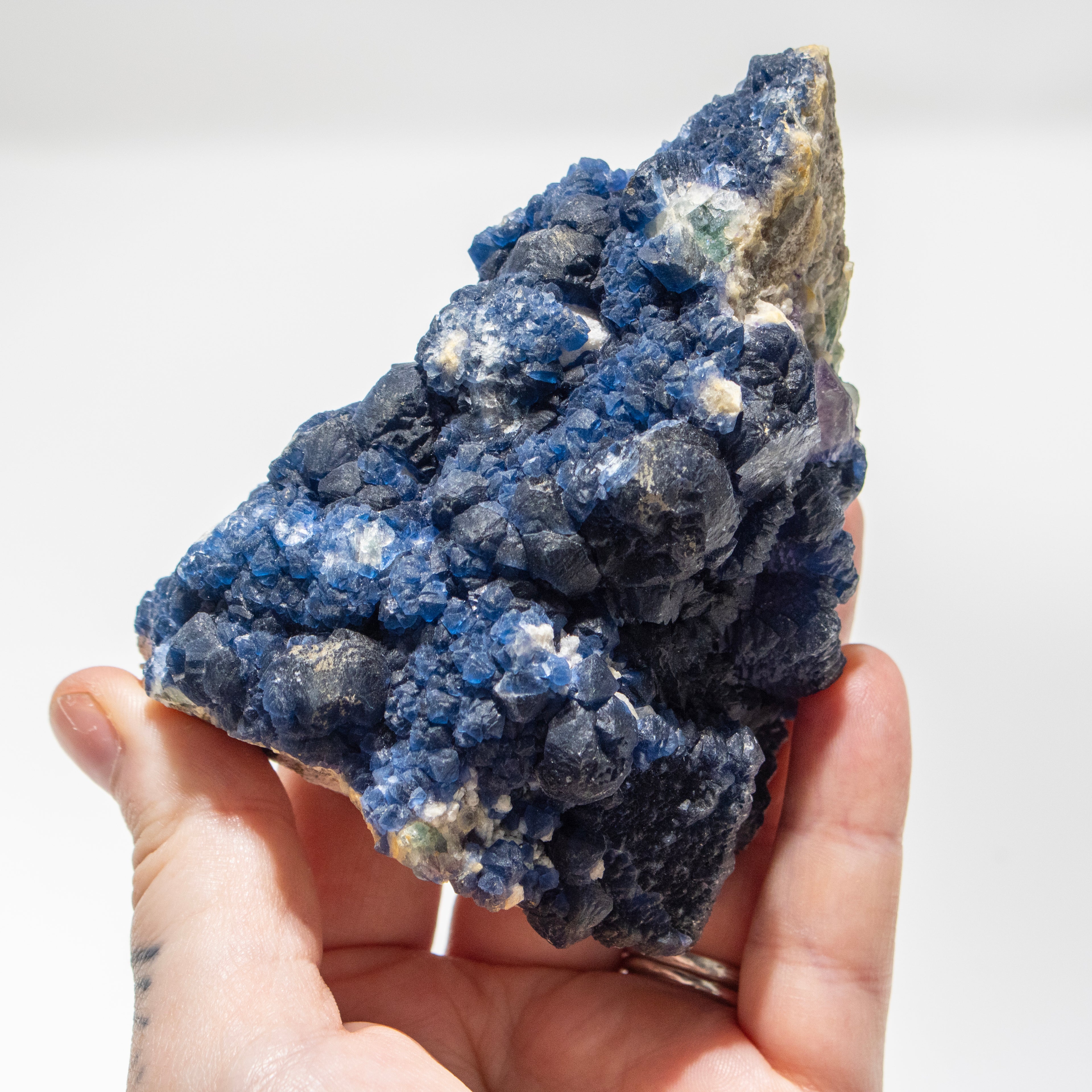 Hand holding a blue crystal rock against a white background
