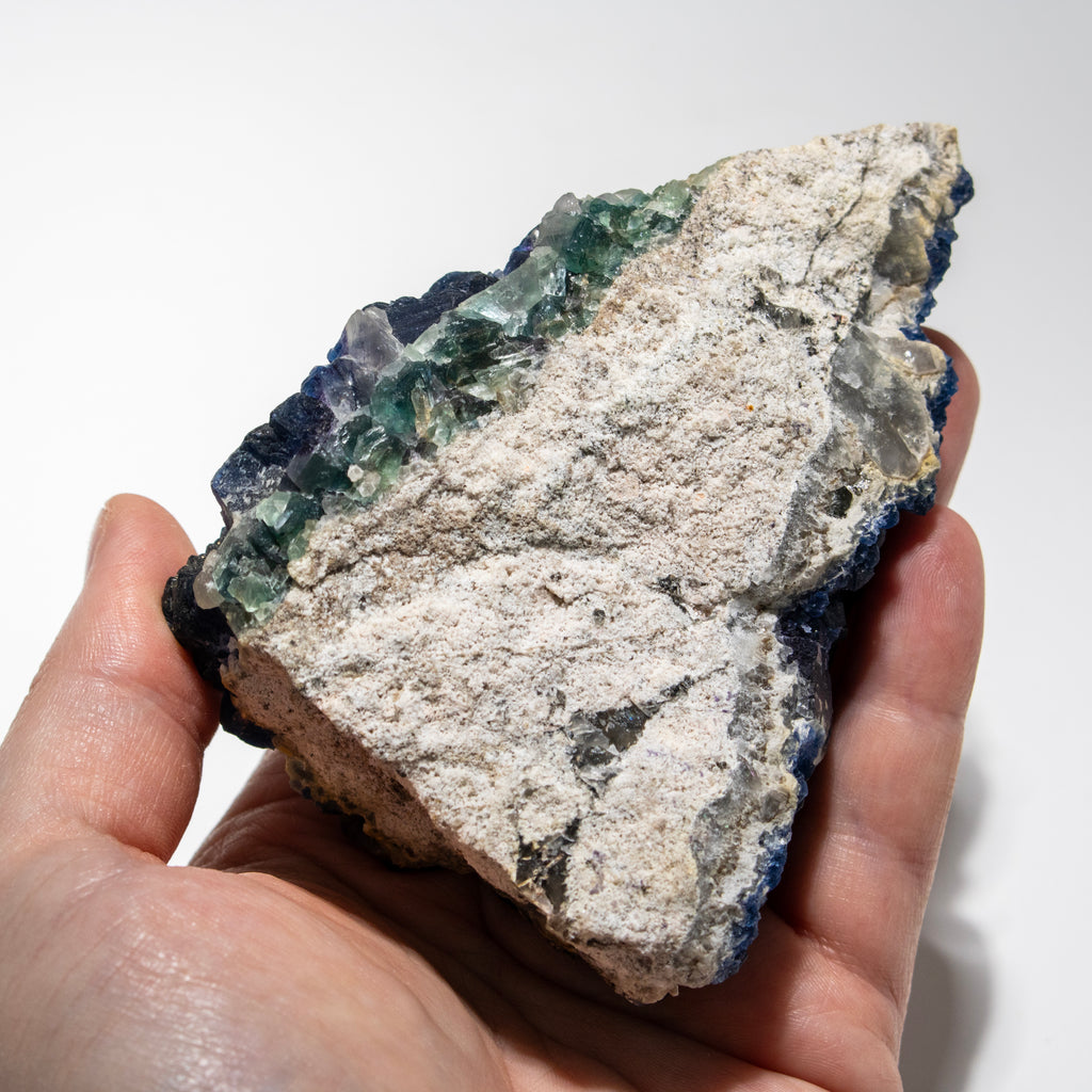 Hand holding a large crystal rock with a white background